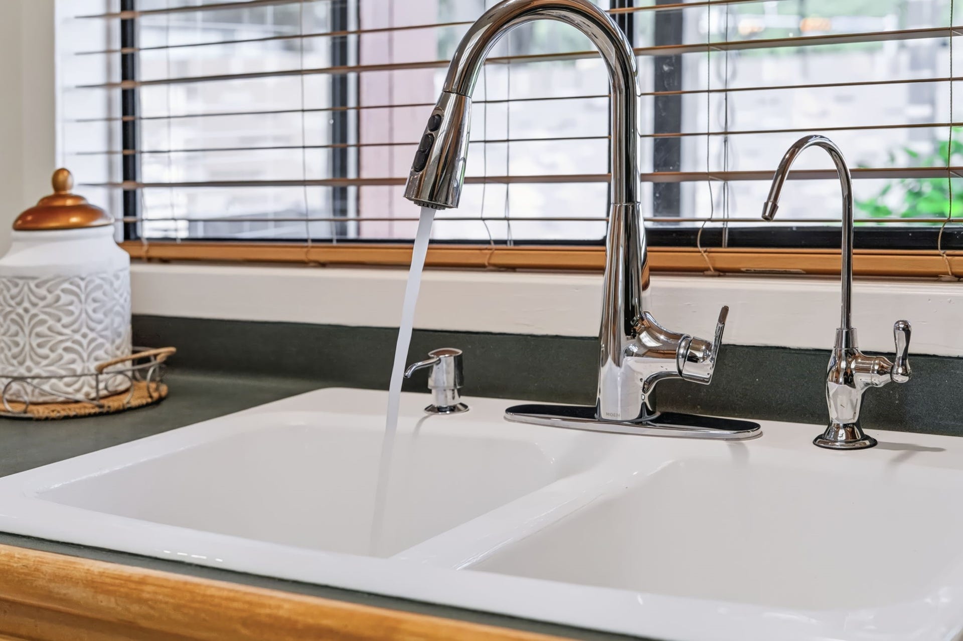 1802 Brushy Creek Drive, Sugar Land, TX 77478 A double porcelain sink features a gooseneck pull-down faucet and a separate water filtration faucet, while the window above offers a relaxing view of the backyard.