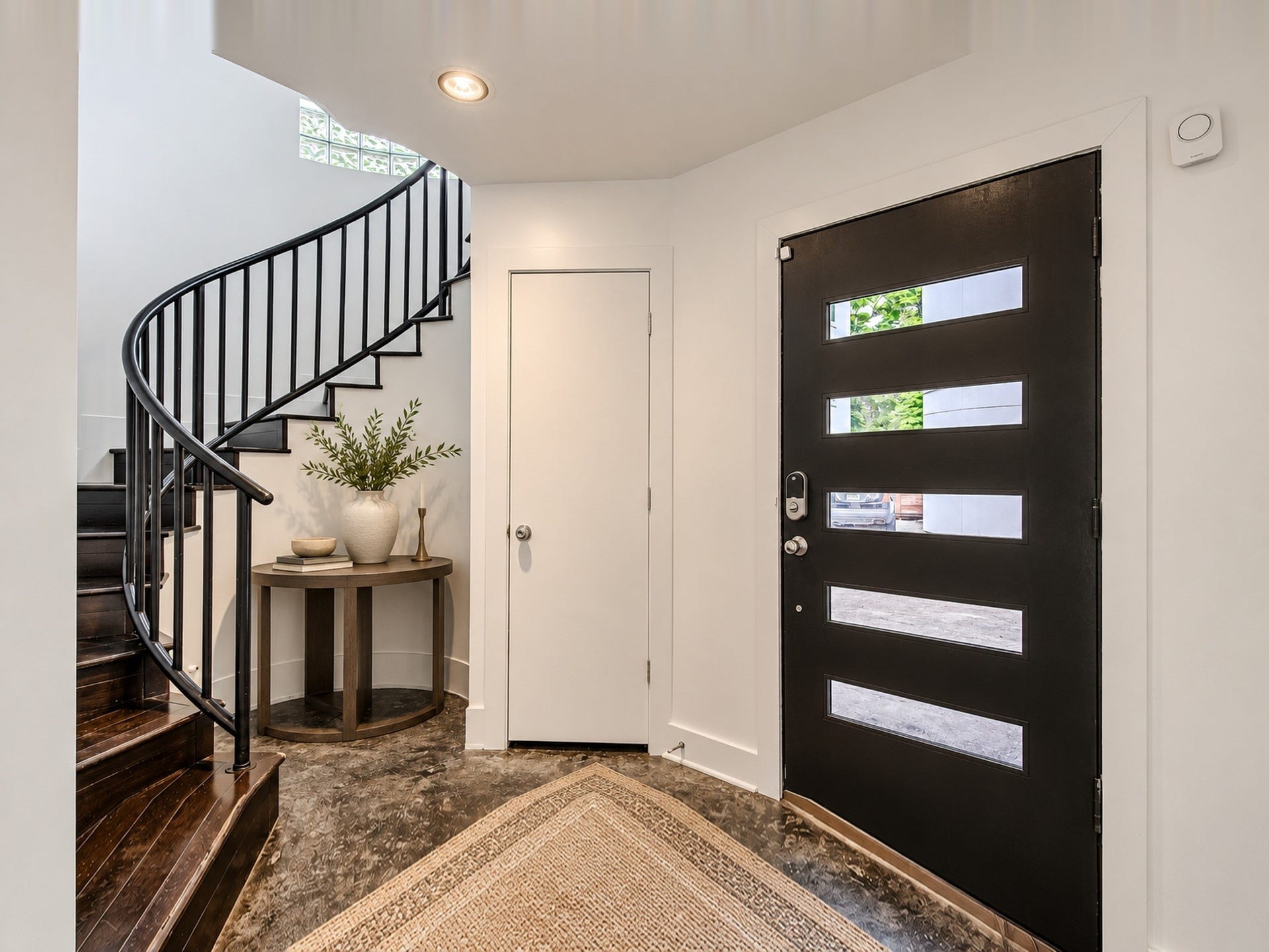2025 Colquitt Street, #E, Houston, TX 77098 Welcoming entry featuring a modern glass-paneled door, patterned flooring, and a dramatic curved staircase.