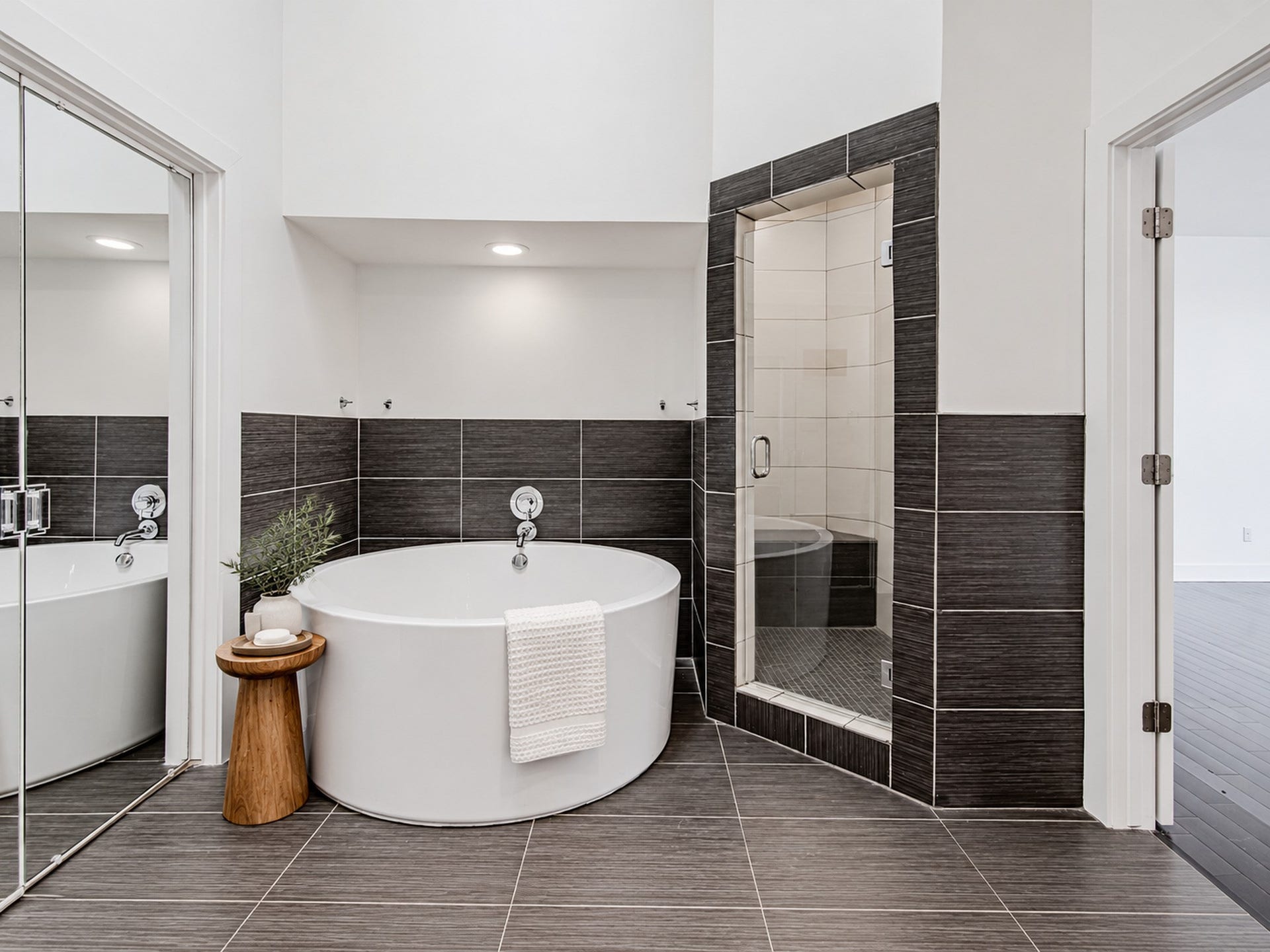 2025 Colquitt Street, #E, Houston, TX 77098 Primary bathing area featuring a freestanding soaking tub, separate glass-enclosed shower, and dark tile accents.