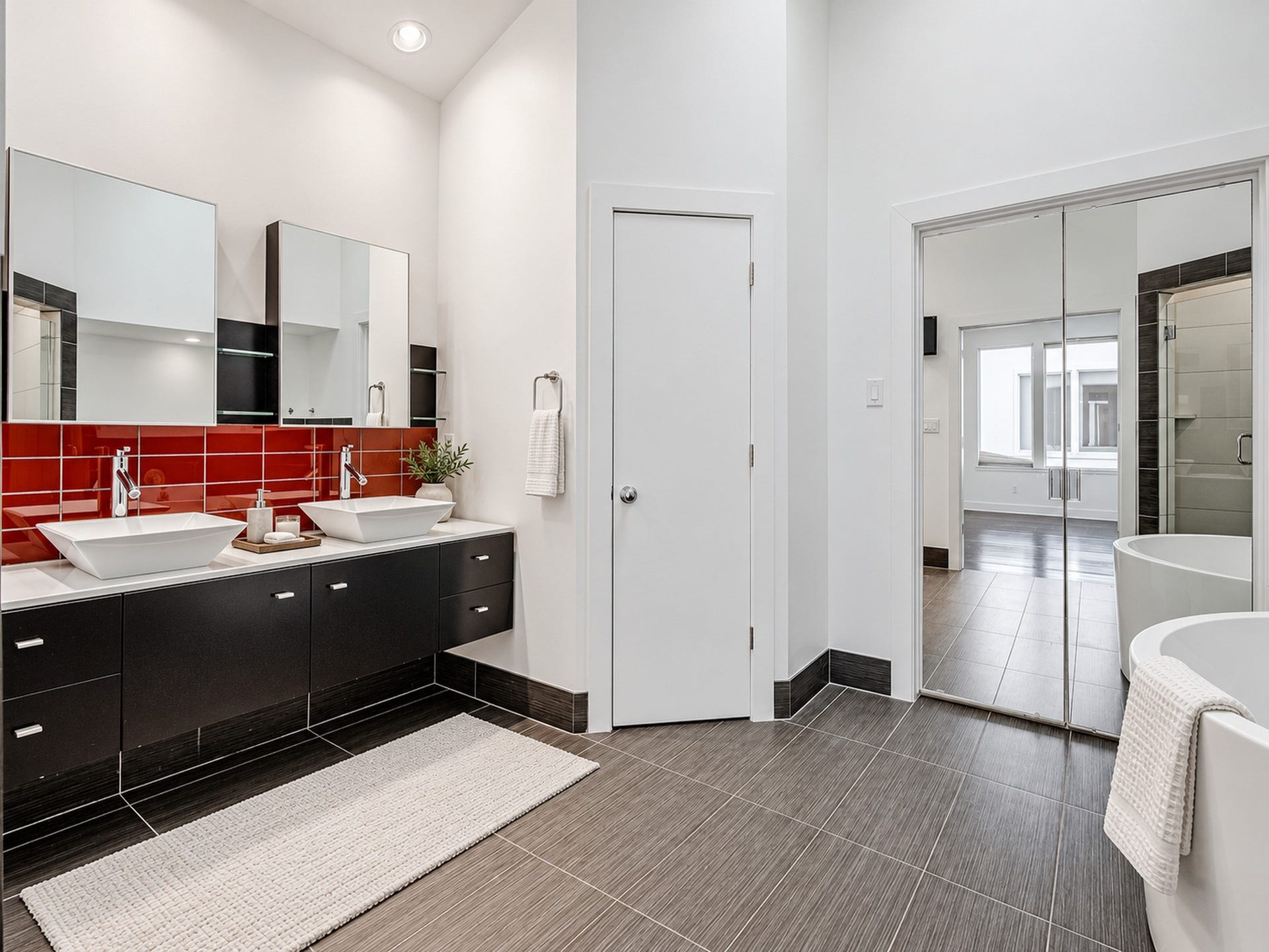 2025 Colquitt Street, #E, Houston, TX 77098 Primary bathroom featuring dual sinks, dark vanity cabinetry, a bold red backsplash, and a separate tub and shower area.