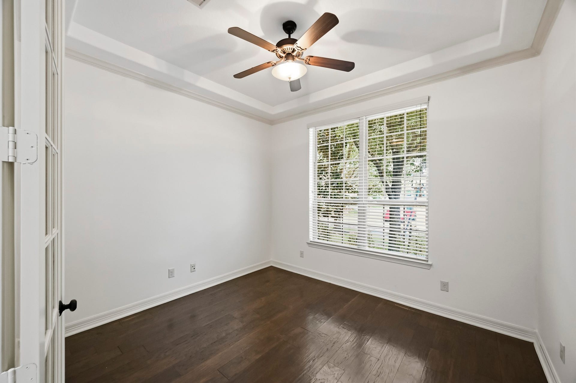 27730 Dalton Bluff Court, Katy, TX 77494 This bright, versatile room features rich wood flooring, neutral walls, and an elegant tray ceiling with crown molding. A large window provides abundant natural light and views of the surrounding greenery, while a ceiling fan with integrated lighting adds everyday comfort. The flexible layout makes this space ideal for use as a secondary bedroom, home office, or additional flex space.