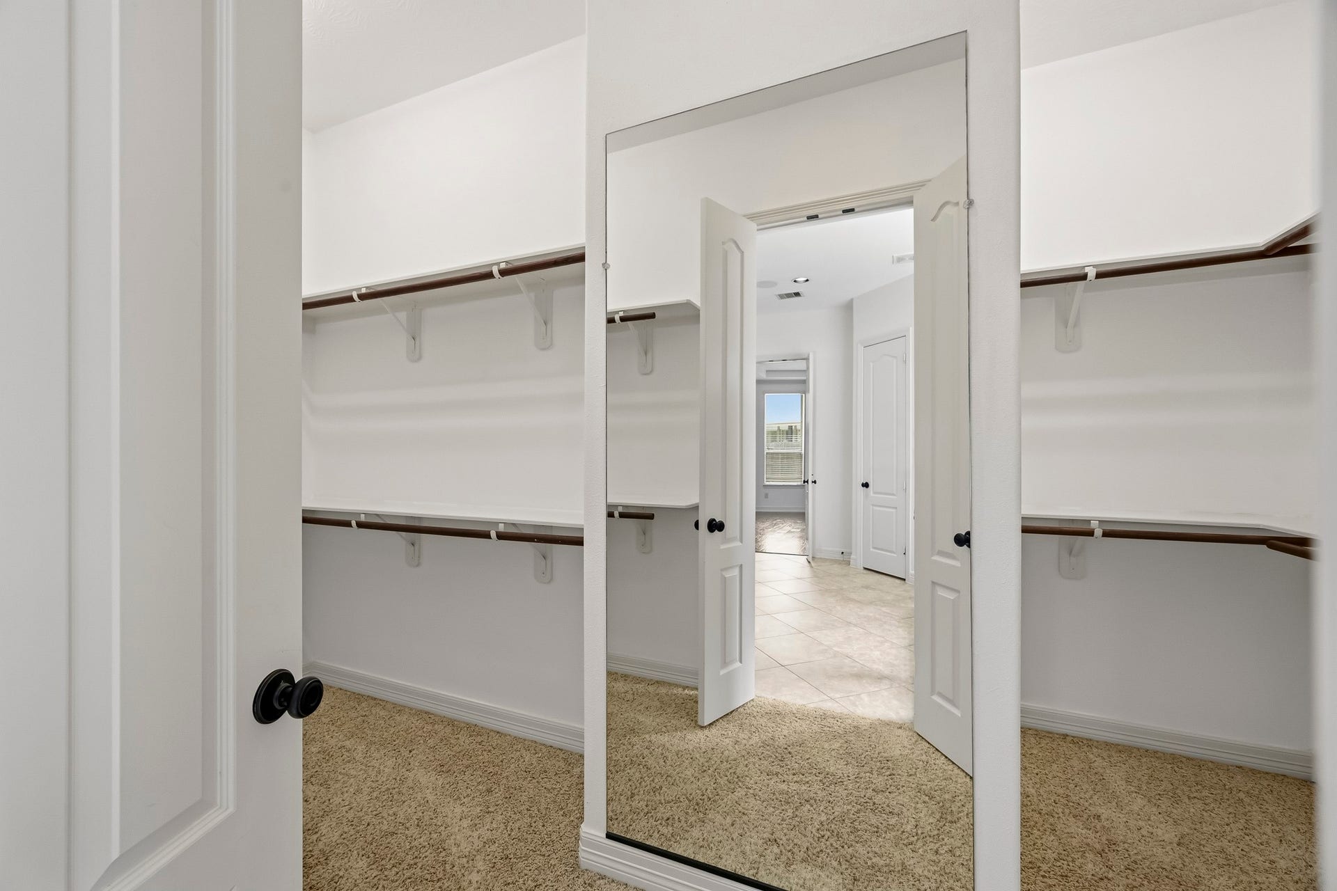 27730 Dalton Bluff Court, Katy, TX 77494 This spacious walk-in closet offers abundant hanging space with dual-level clothing rods along multiple walls. Neutral finishes and plush carpeting create a clean, organized look, while a full-length mirror adds convenience and enhances the sense of space.