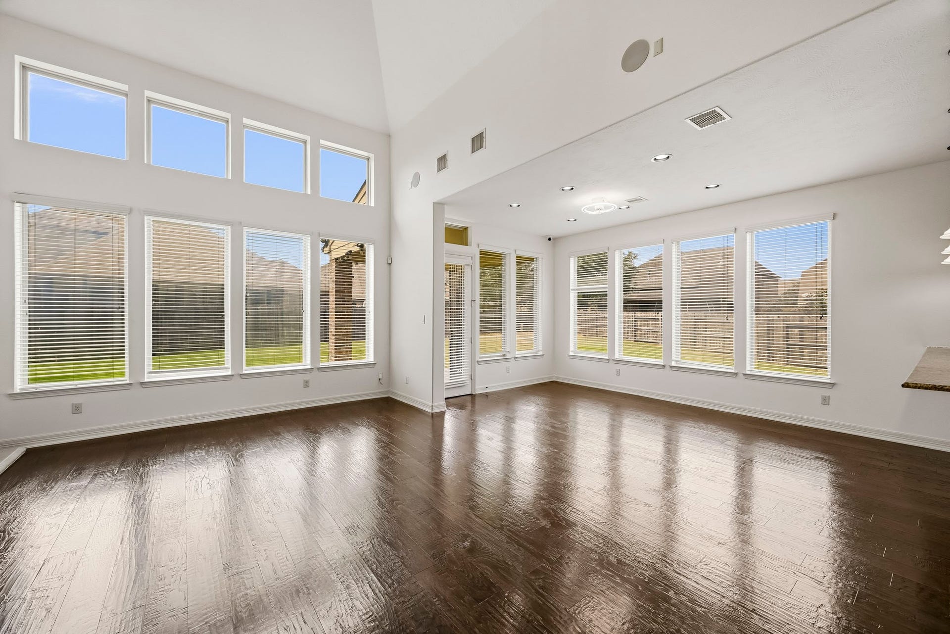 27730 Dalton Bluff Court, Katy, TX 77494 This impressive open-concept living area features soaring ceilings, rich wood flooring, and an abundance of natural light from expansive two-story windows. The spacious layout flows seamlessly into an adjoining dining area.