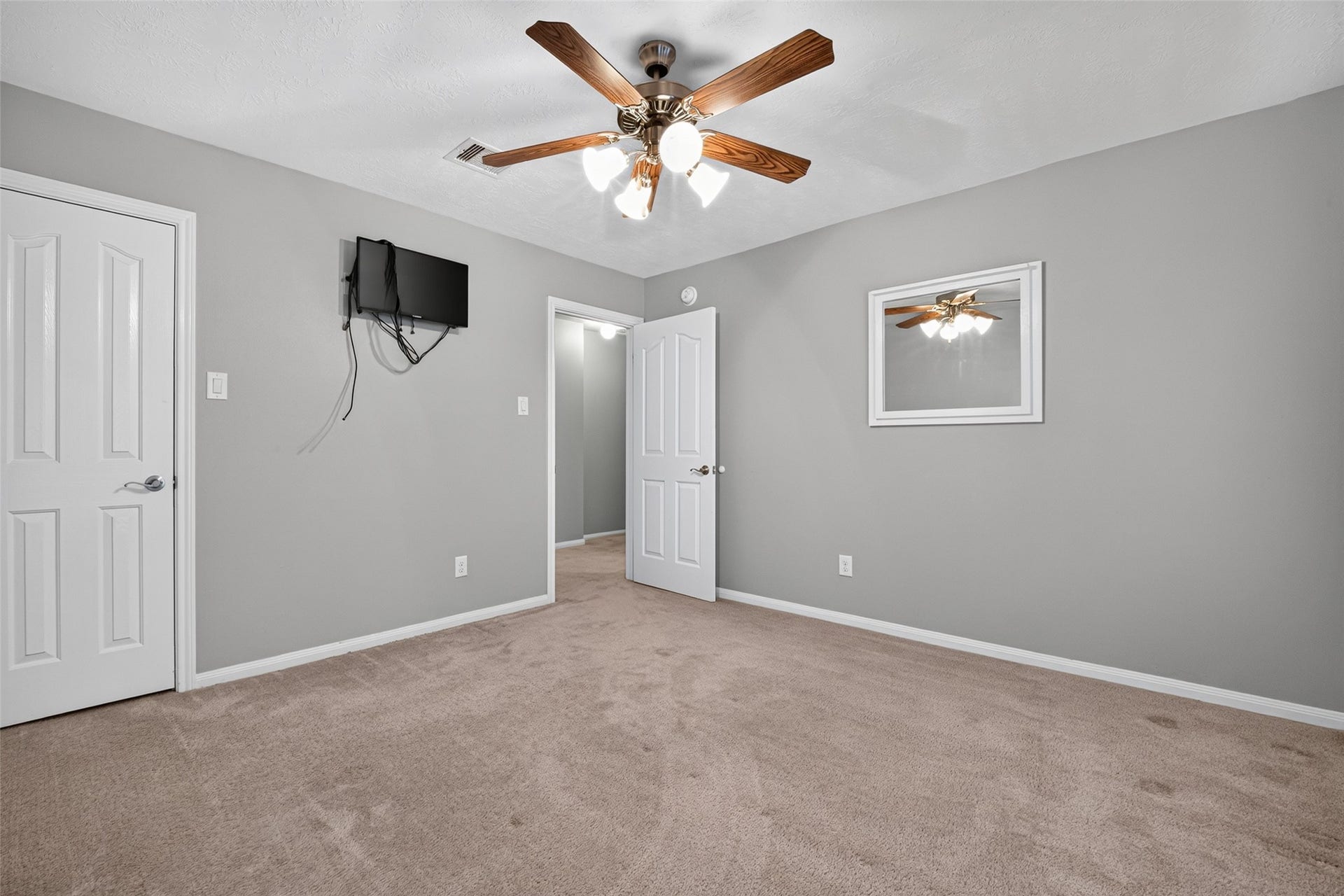Reverse secondary-bedroom view shows the entry, closet door, ceiling fan, and carpeted floor area available for furniture placement.