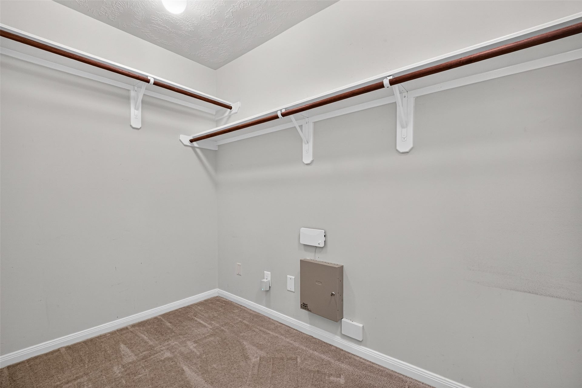 Primary closet features overhead shelving and hanging rods.