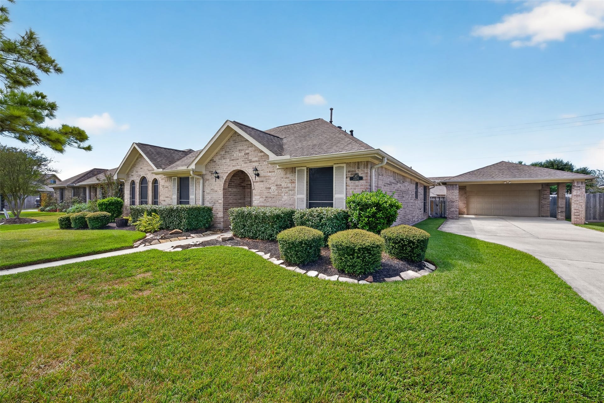 Angled exterior view showcases the homes brick facade, multiple roof gables, decorative shutters, and established landscaping along the front elevation.