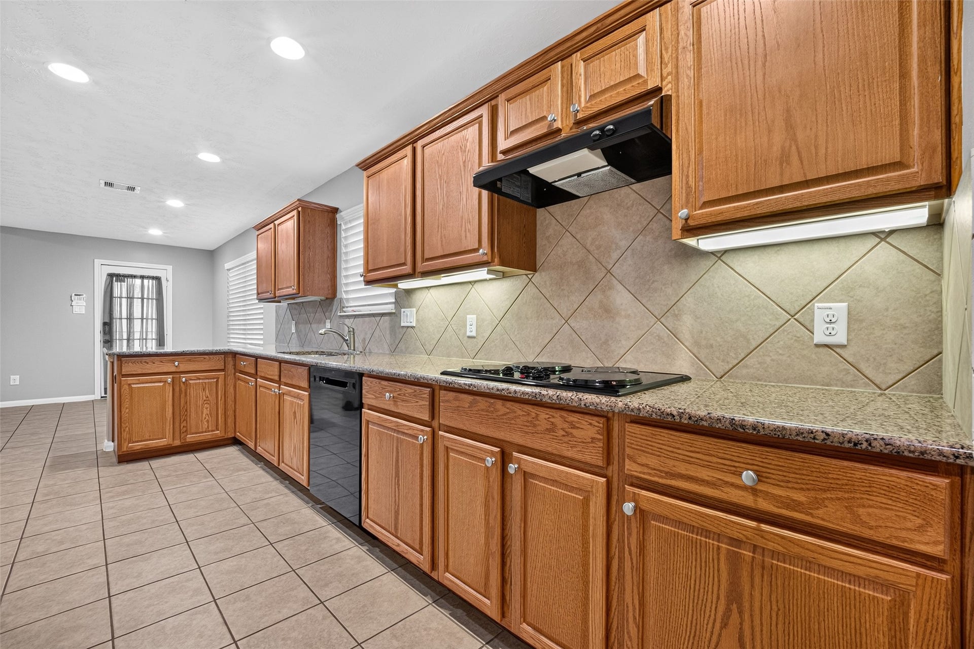 Extended kitchen countertops with wood cabinetry, and tile backsplash.