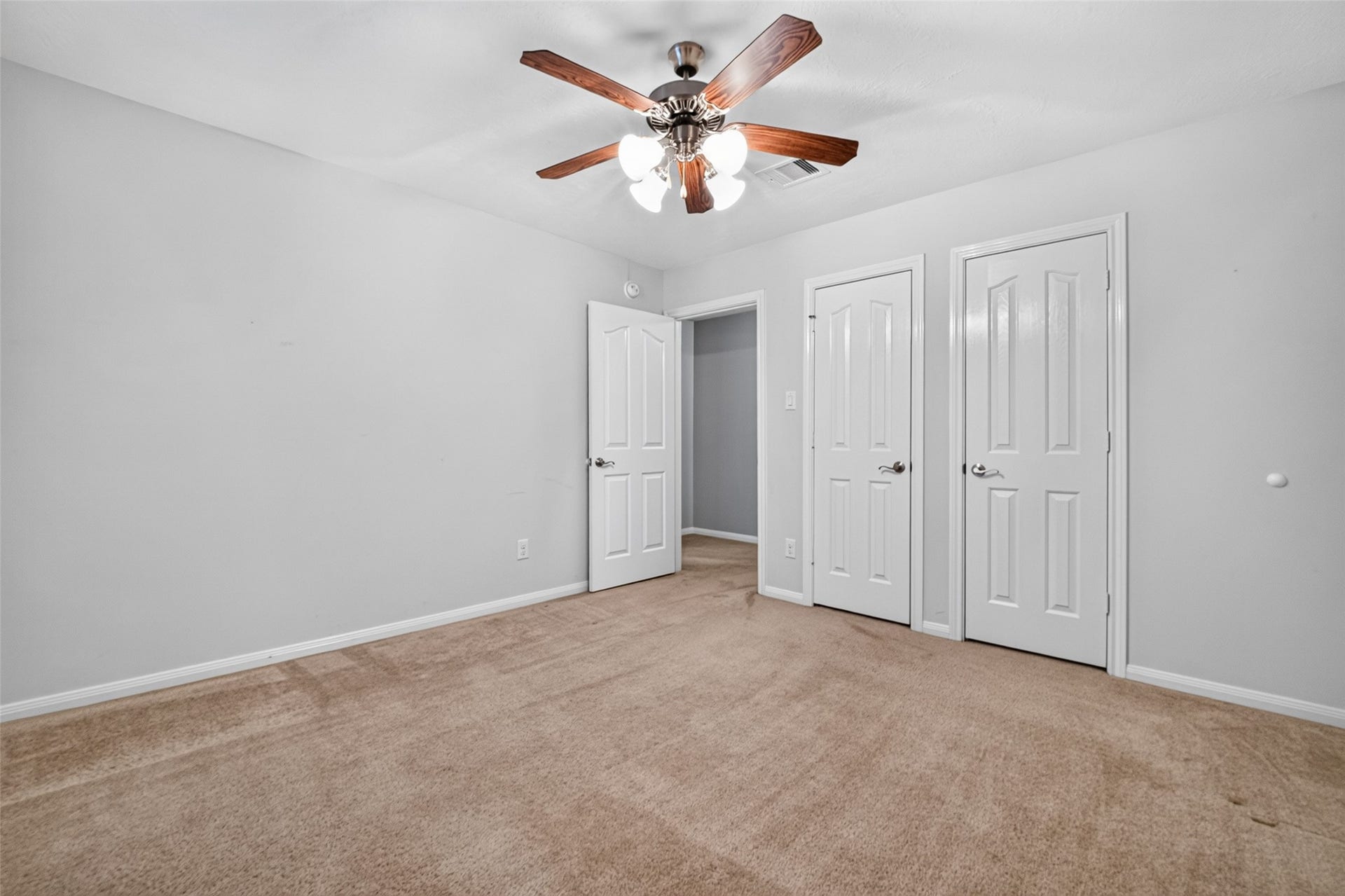 Bedroom three includes double closet doors, carpeted flooring, and a ceiling fan, with the rooms entry positioned along the same wall.
