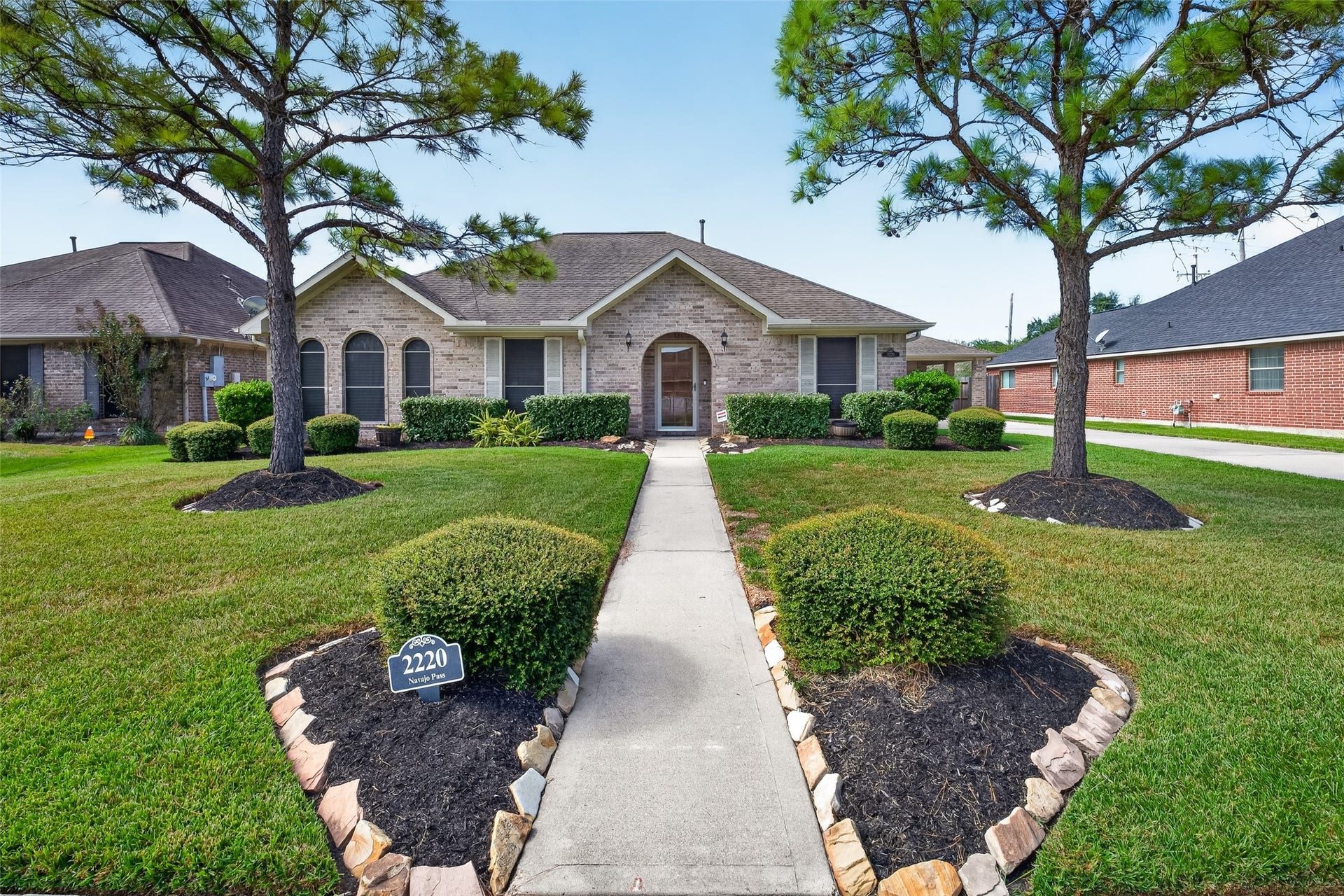 Angled exterior view showcases the homes brick facade, multiple roof gables, decorative shutters, and established landscaping along the front elevation.