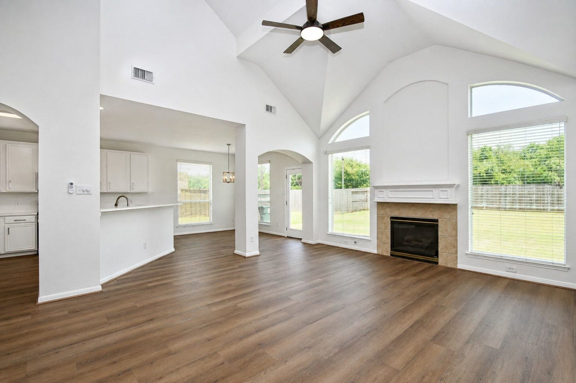 9111 Morningstar Drive, Sugar Land, TX 77479 Stunning open-concept living space with vaulted ceilings, large windows for natural light, and a cozy fireplace, seamlessly flowing into a bright kitchen area.