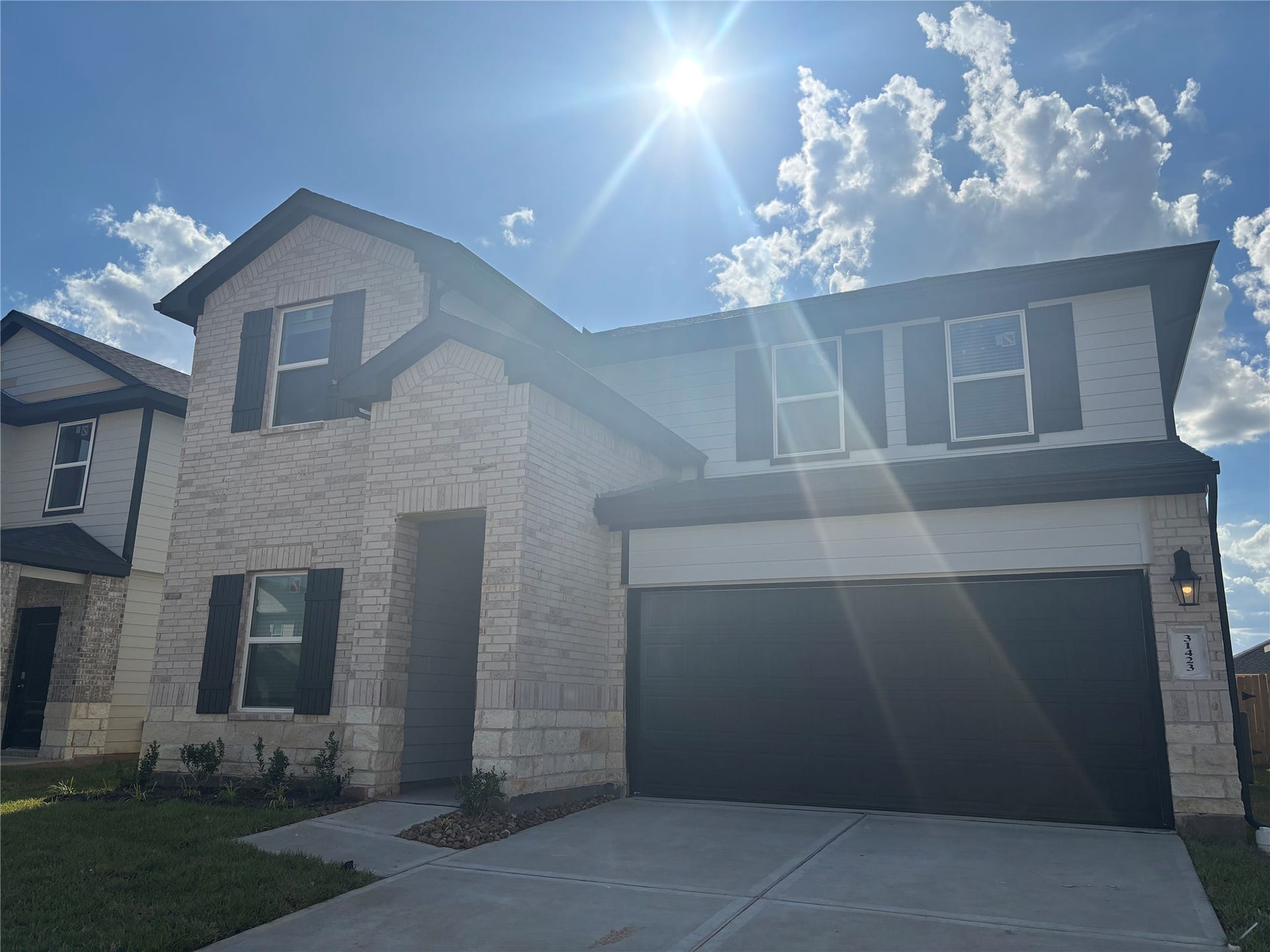 Modern two-story home with a brick facade and attached two-car garage, set against a clear blue sky.