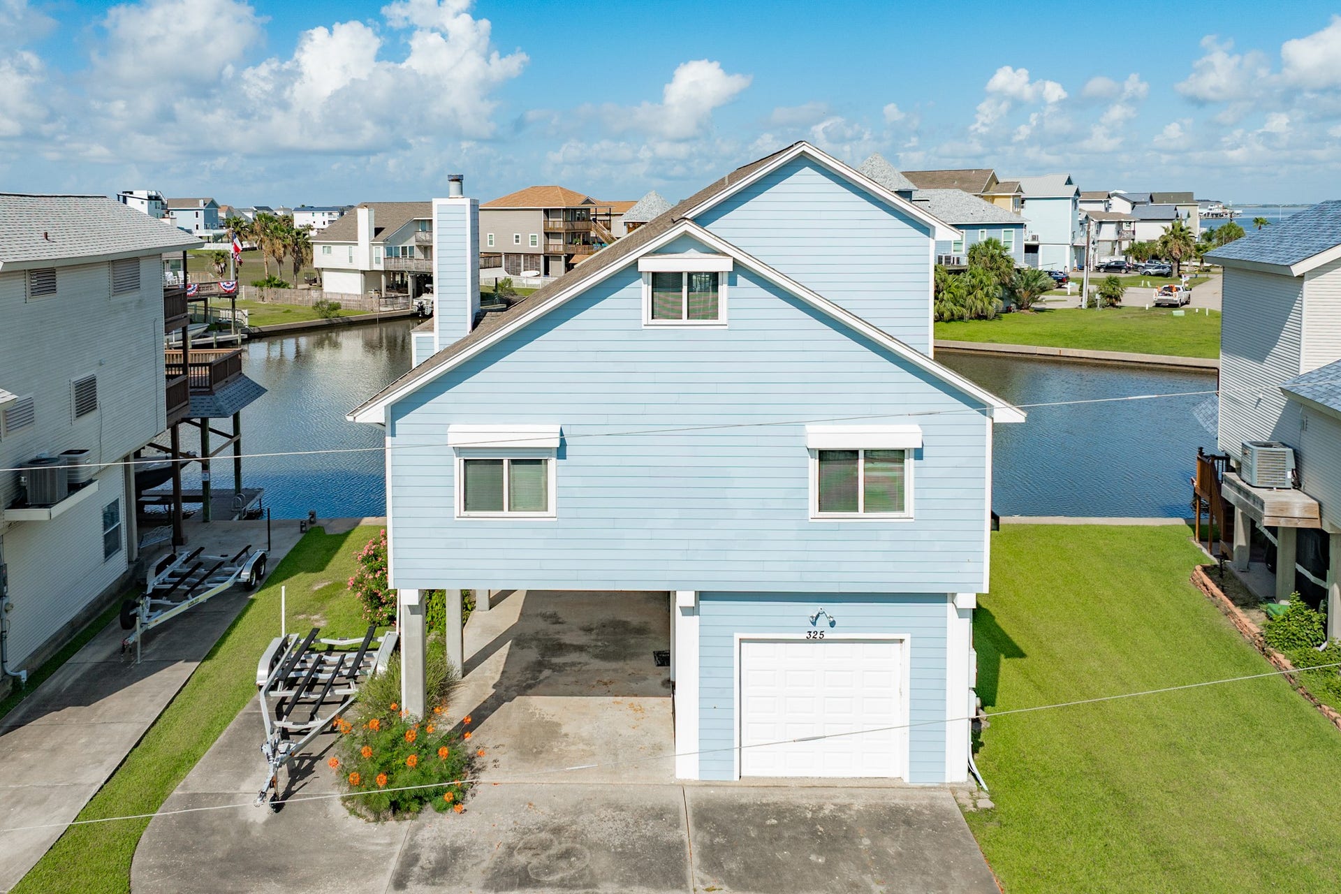 325 Admiral Circle, Tiki Island, TX 77554 Property has a double wide driveway, parking under home, 1 car garage and as a bonus, concrete pad to park your boat trailer.
