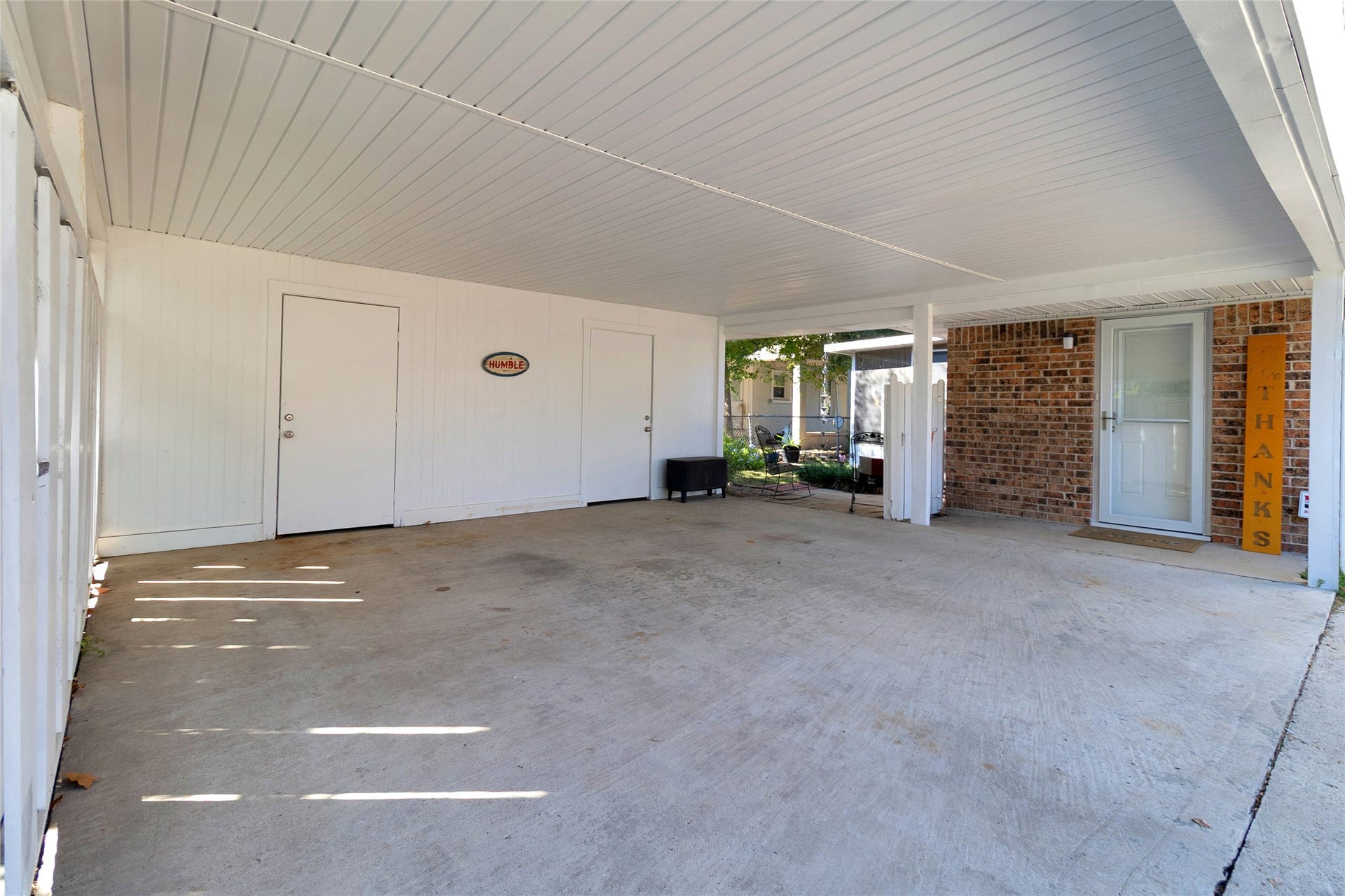 613 N Avenue F, Humble, TX 77338 Spacious covered carport with clean lines and direct access to a welcoming brick entrance.
