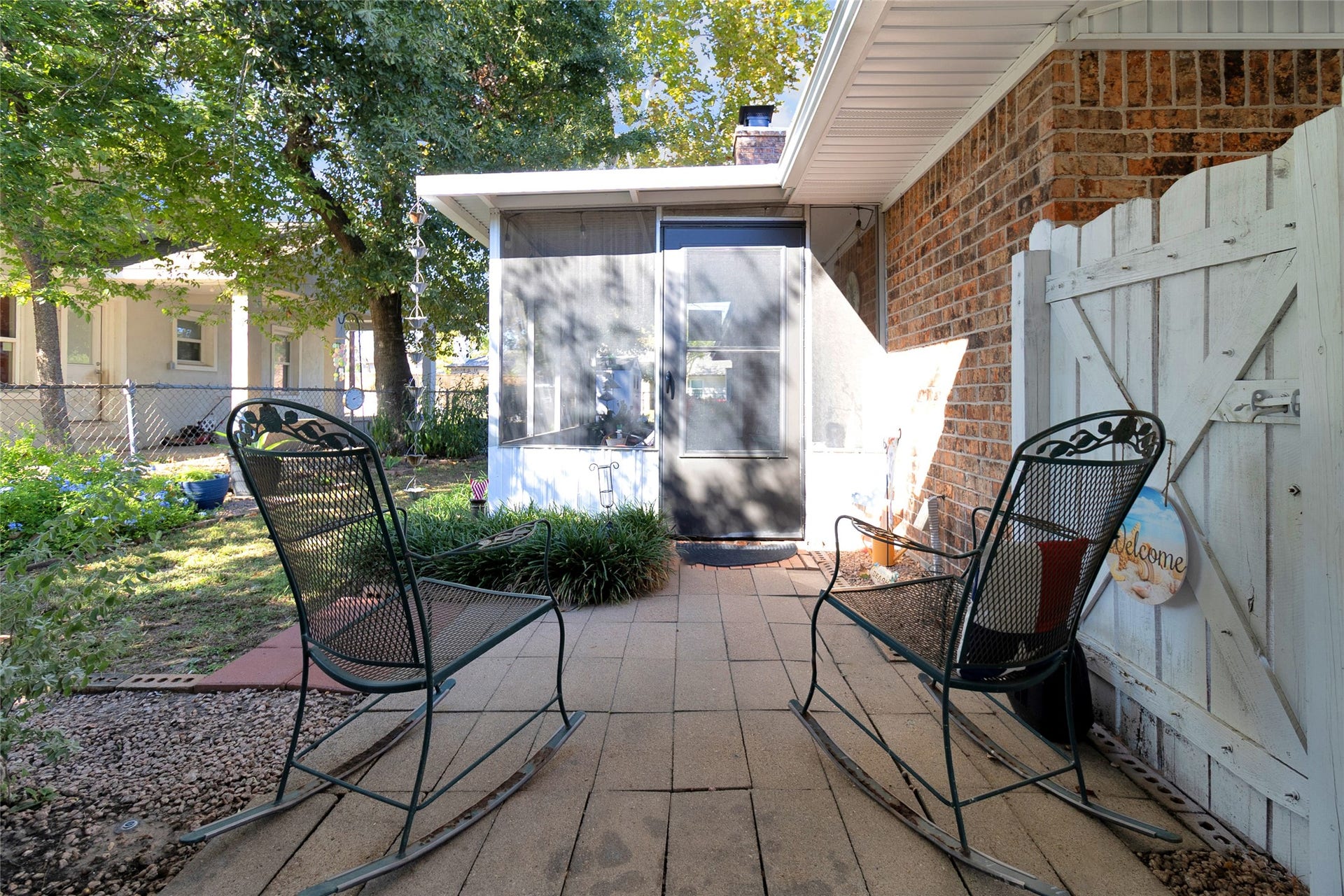 613 N Avenue F, Humble, TX 77338 Charming patio area featuring a cozy seating arrangement with metal rocking chairs, surrounded by lush greenery and a welcoming atmosphere.