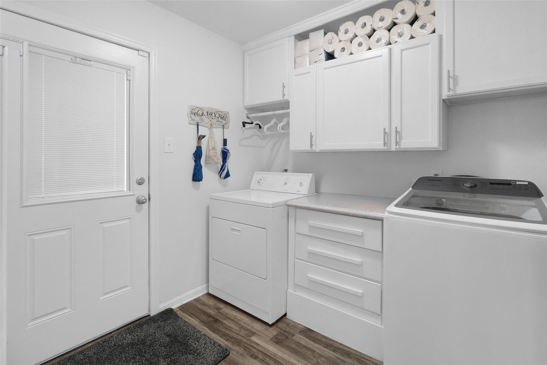 613 N Avenue F, Humble, TX 77338 Bright and efficient laundry room with ample storage, featuring upper cabinets filled with essentials and modern appliances for all your laundry needs.