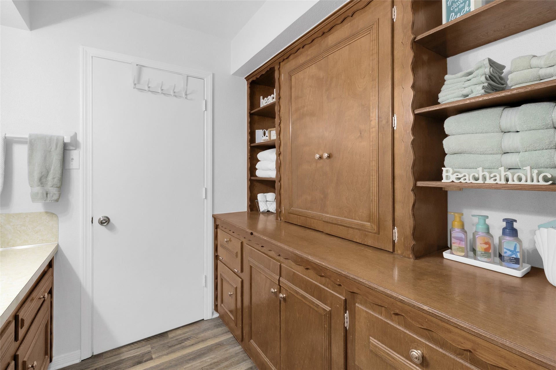 613 N Avenue F, Humble, TX 77338 Charming bathroom with ample wooden cabinetry, open shelving, and neatly arranged towels, offering both style and functionality.