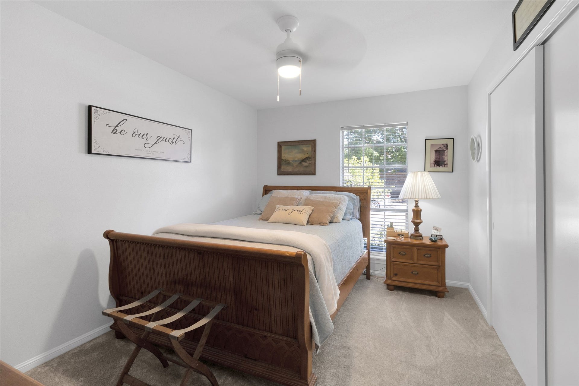 613 N Avenue F, Humble, TX 77338 First bedroom with a warm, inviting atmosphere, featuring a wooden bed, plush carpeting, and ample natural light from a large window.