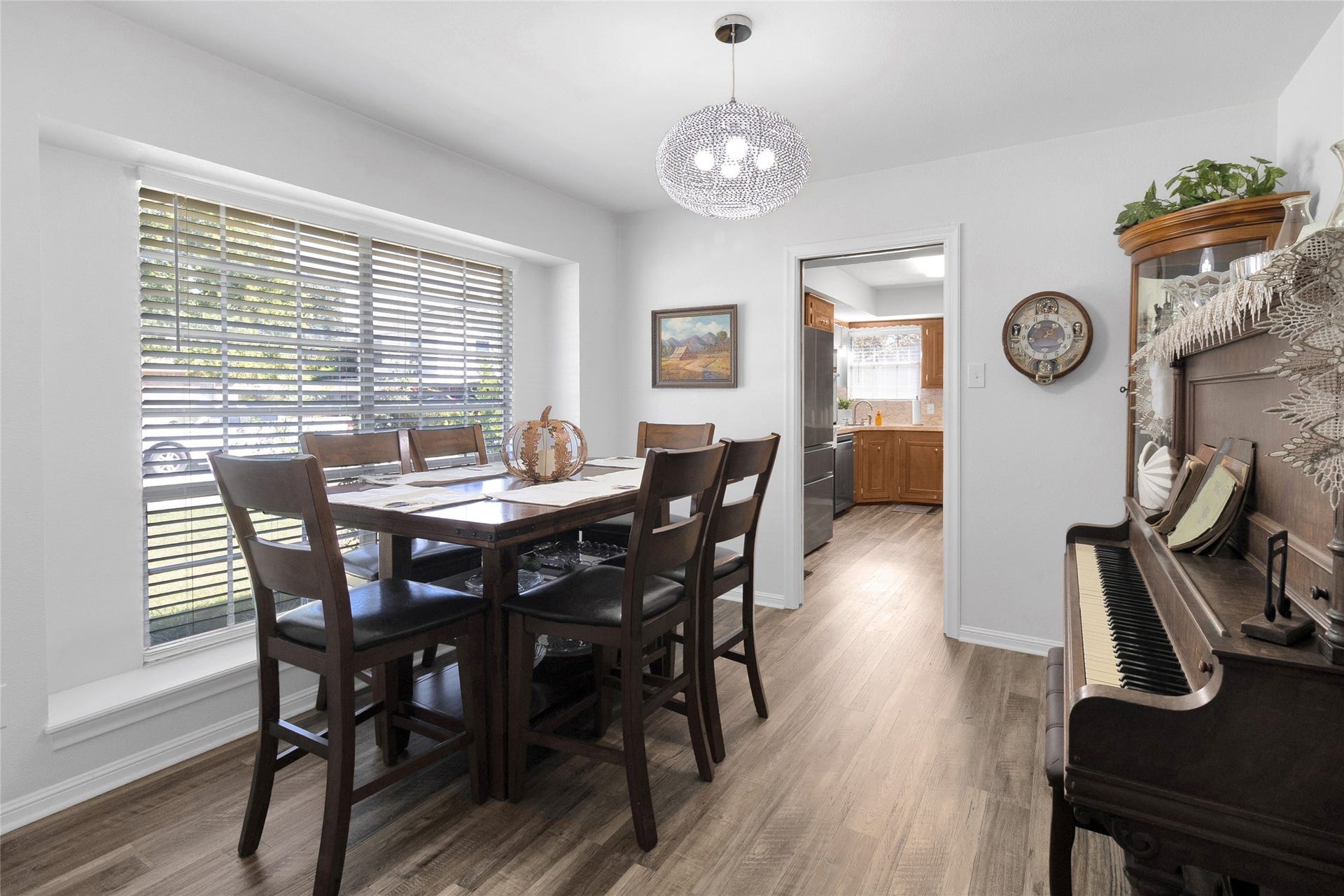 613 N Avenue F, Humble, TX 77338 Elegant dining area with abundant natural light, featuring a stylish chandelier, cozy piano nook, and seamless access to the adjacent kitchen.