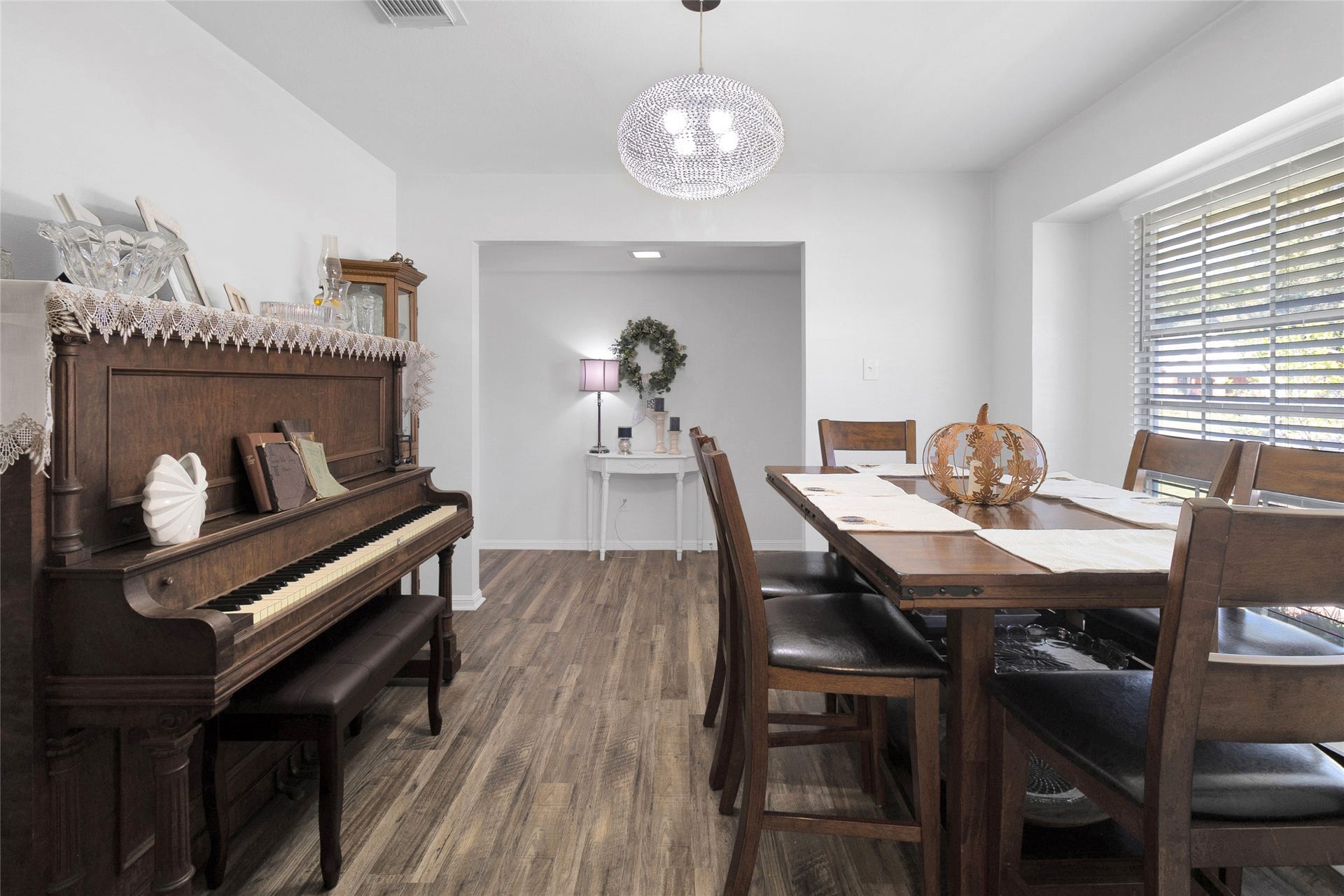 613 N Avenue F, Humble, TX 77338 Charming dining area featuring a classic wood piano and a large window that fills the room with natural light, creating a warm and inviting atmosphere for gatherings.