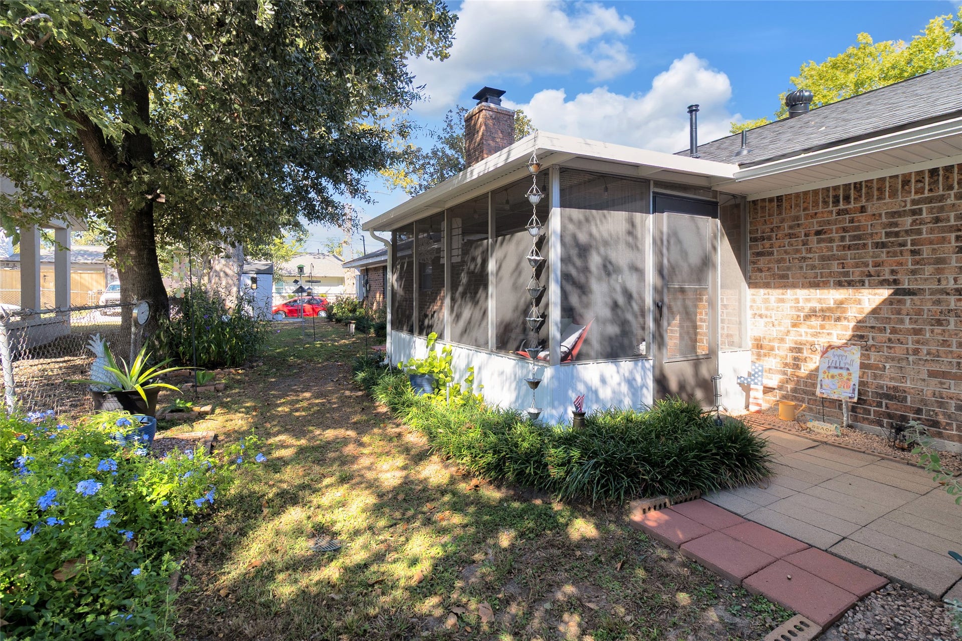 613 N Avenue F, Humble, TX 77338 Charming backyard features a cozy screened-in porch, perfect for relaxing while enjoying the surrounding lush greenery and mature trees.