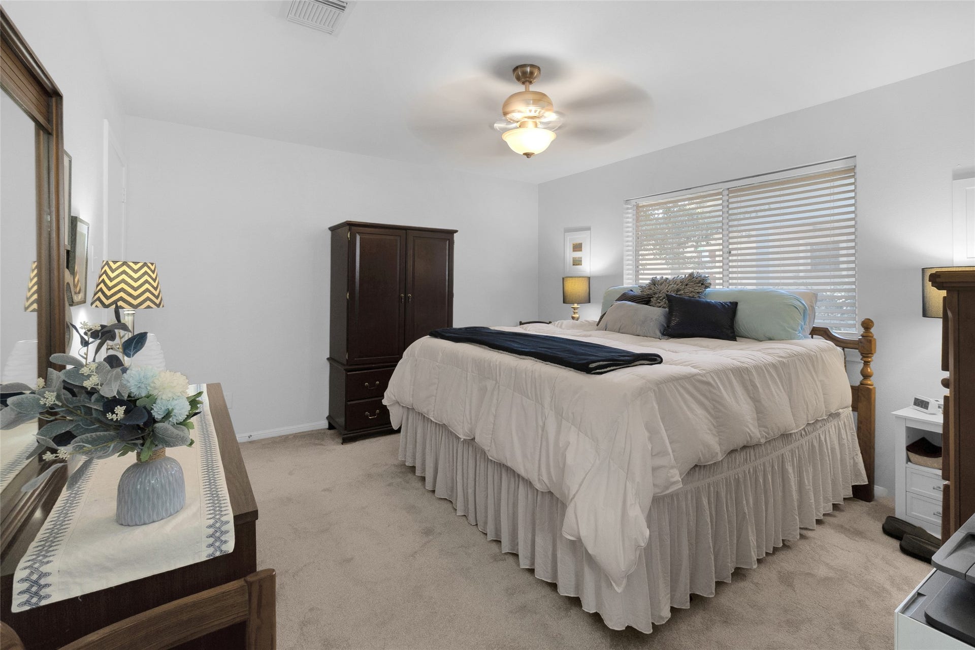 613 N Avenue F, Humble, TX 77338 Angled view of the bedroom with soft carpeting, a comfortable bed, and ample natural light from large windows.