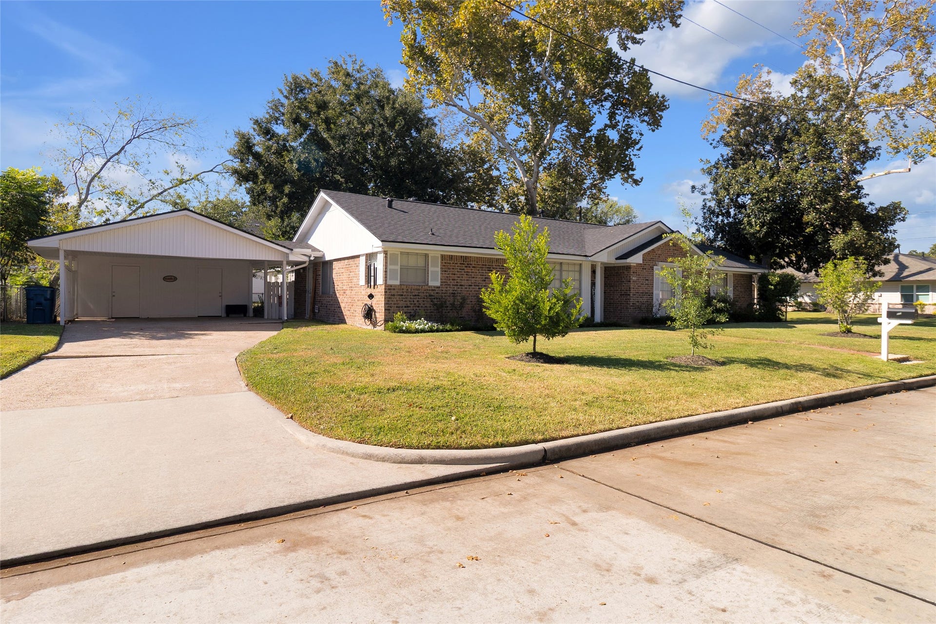 613 N Avenue F, Humble, TX 77338 Angled view of the home showcasing its spacious driveway and convenient attached carport, offering ample parking space.