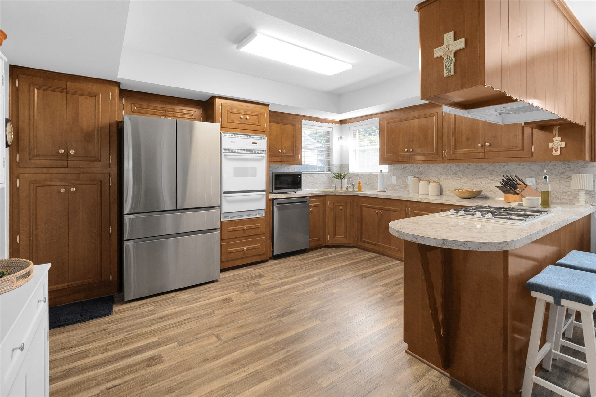613 N Avenue F, Humble, TX 77338 Spacious kitchen with warm wooden cabinetry, stainless steel appliances, and a large countertop with seating, perfect for cooking and entertaining.