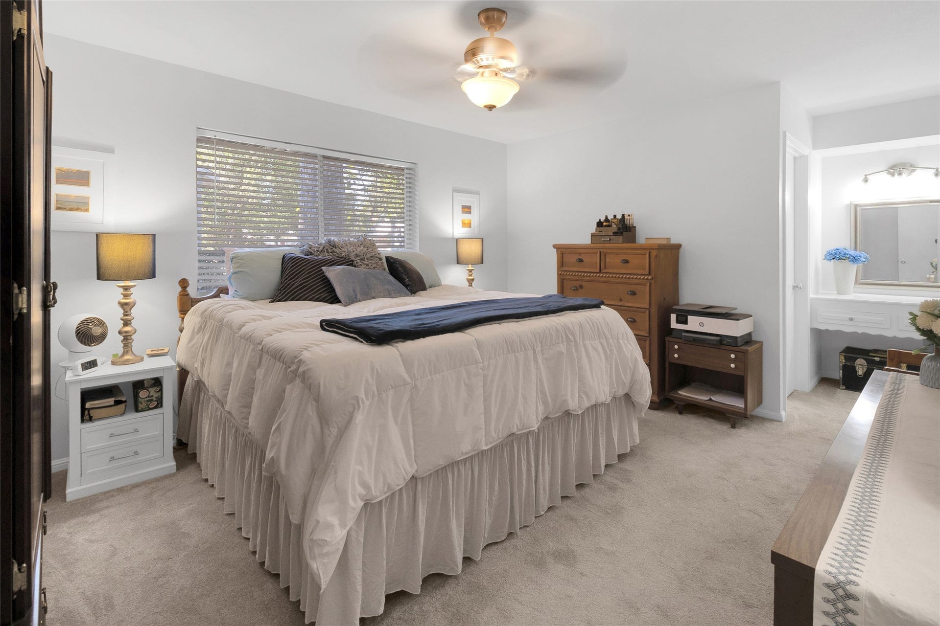 613 N Avenue F, Humble, TX 77338 Primary bedroom featuring a plush, inviting bed, warm wood accents, and ample natural light from a large window, creating a tranquil retreat.