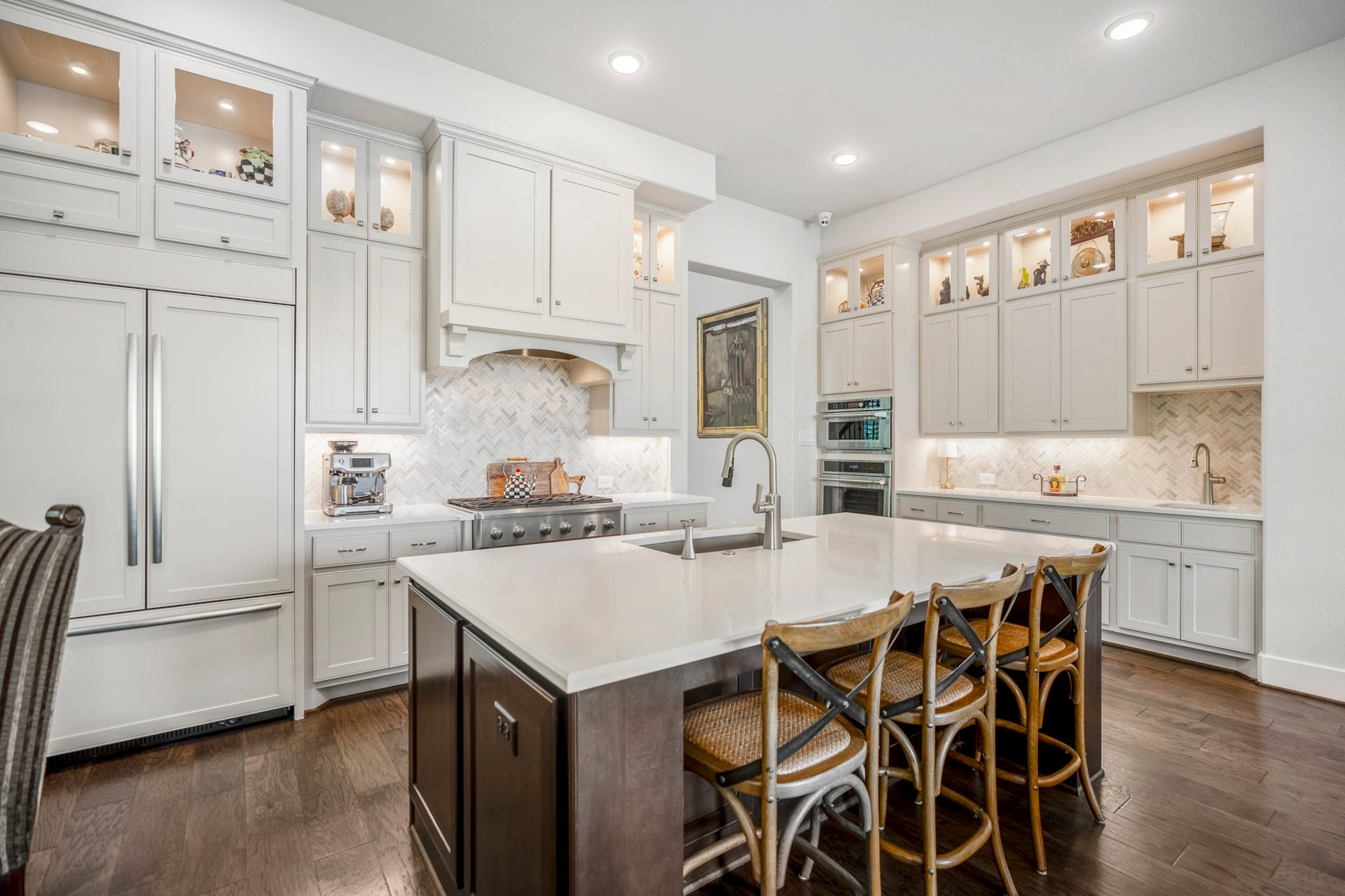 The built-in wood fronted fridge is by Jenn Aire. The sellers added the upper cabinets and lighting, as well as the sink in the bar.  Quartz counter tops complete the look.