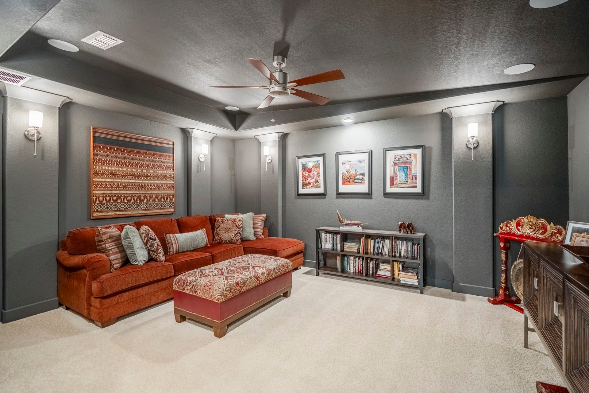 The media room, with sconce lighting, dark paint, and carpet to muffle the sound.