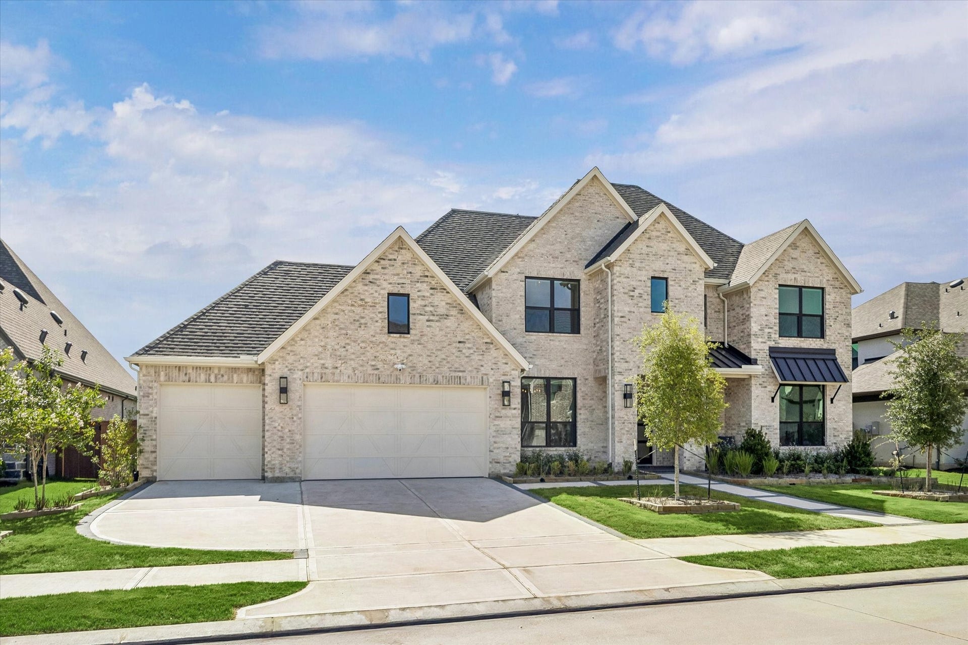 IMPRESSIVE TWO-STORY BRICK EXTERIOR WITH A THREE-CAR GARAGE, MULTIPLE ROOFLINES, AND A WIDE DRIVEWAY.