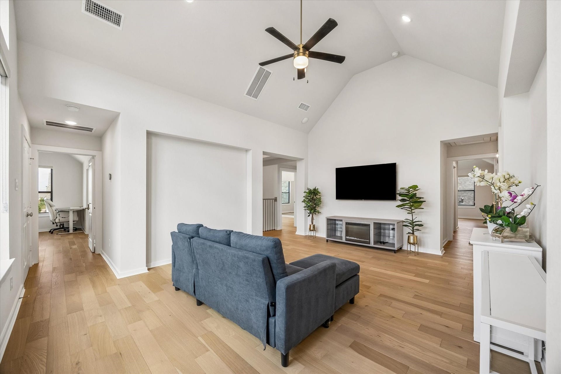 UPSTAIRS GAME ROOM FEATURES A VAULTED CEILING, CEILING FAN, WOOD FLOORING, AND OPEN ACCESS TO MULTIPLE SECONDARY ROOMS.
