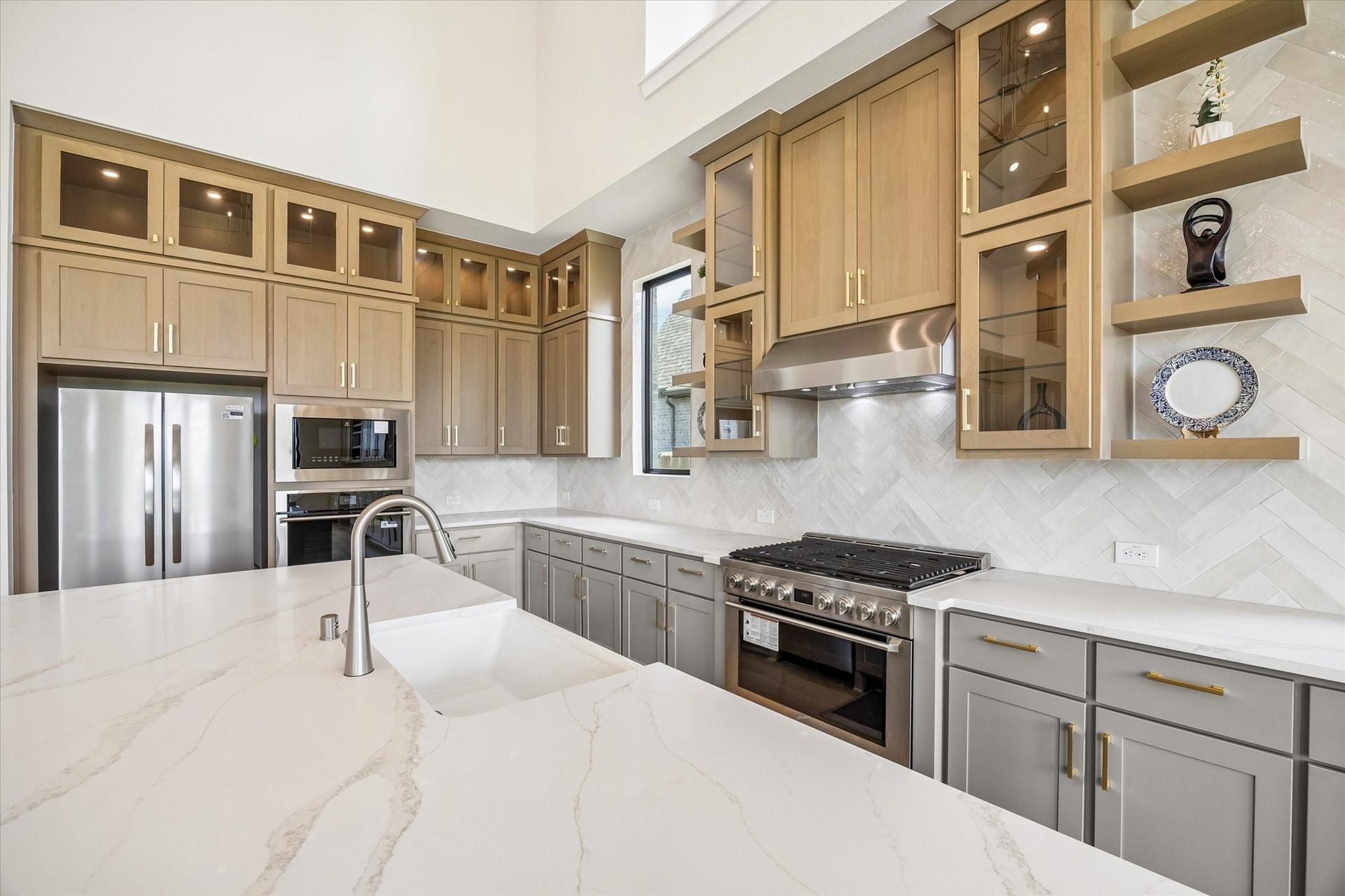 CHEF-INSPIRED KITCHEN INCLUDES CEILING-HEIGHT CABINETRY, GLASS-FRONT DISPLAY CABINETS, OPEN SHELVING, A LARGE GAS RANGE WITH STATEMENT VENT HOOD, QUARTZ SURFACES, AND A HERRINGBONE TILE BACKSPLASH.