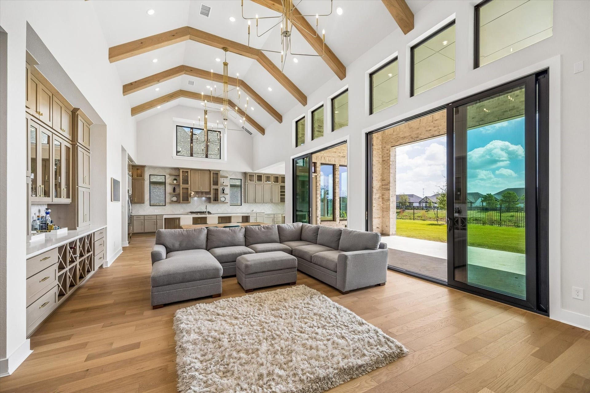 THE FAMILY ROOM OFFERS EXPANSIVE WINDOWS, SLIDING GLASS DOORS, AND WIDE-PLANK WOOD FLOORING. FROM THIS ANGLE, THE OPEN LAYOUT AND CONNECTION TO THE KITCHEN AND OUTDOOR LIVING SPACE ARE ON FULL DISPLAY.