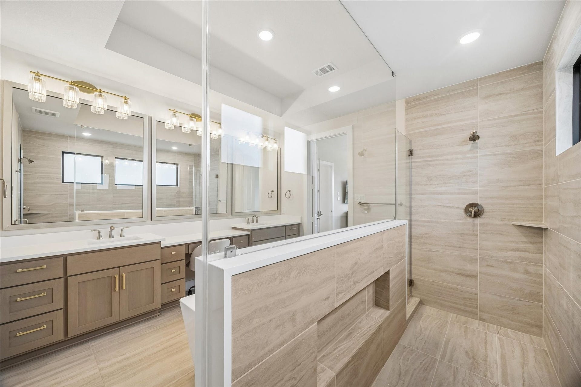 THE PRIMARY SHOWER INCLUDES FRAMELESS GLASS, FULL-HEIGHT TILE, BUILT-IN LEDGES, AND A GENEROUS WALK-IN DESIGN ADJACENT TO THE DUAL VANITIES.