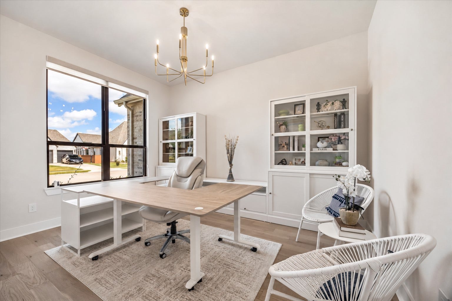 PRIVATE HOME OFFICE OFFERS A LARGE FRONT-FACING WINDOW, WOOD FLOORING, AND PLENTY OF SPACE FOR A FUNCTIONAL WORK-FROM-HOME SETUP.