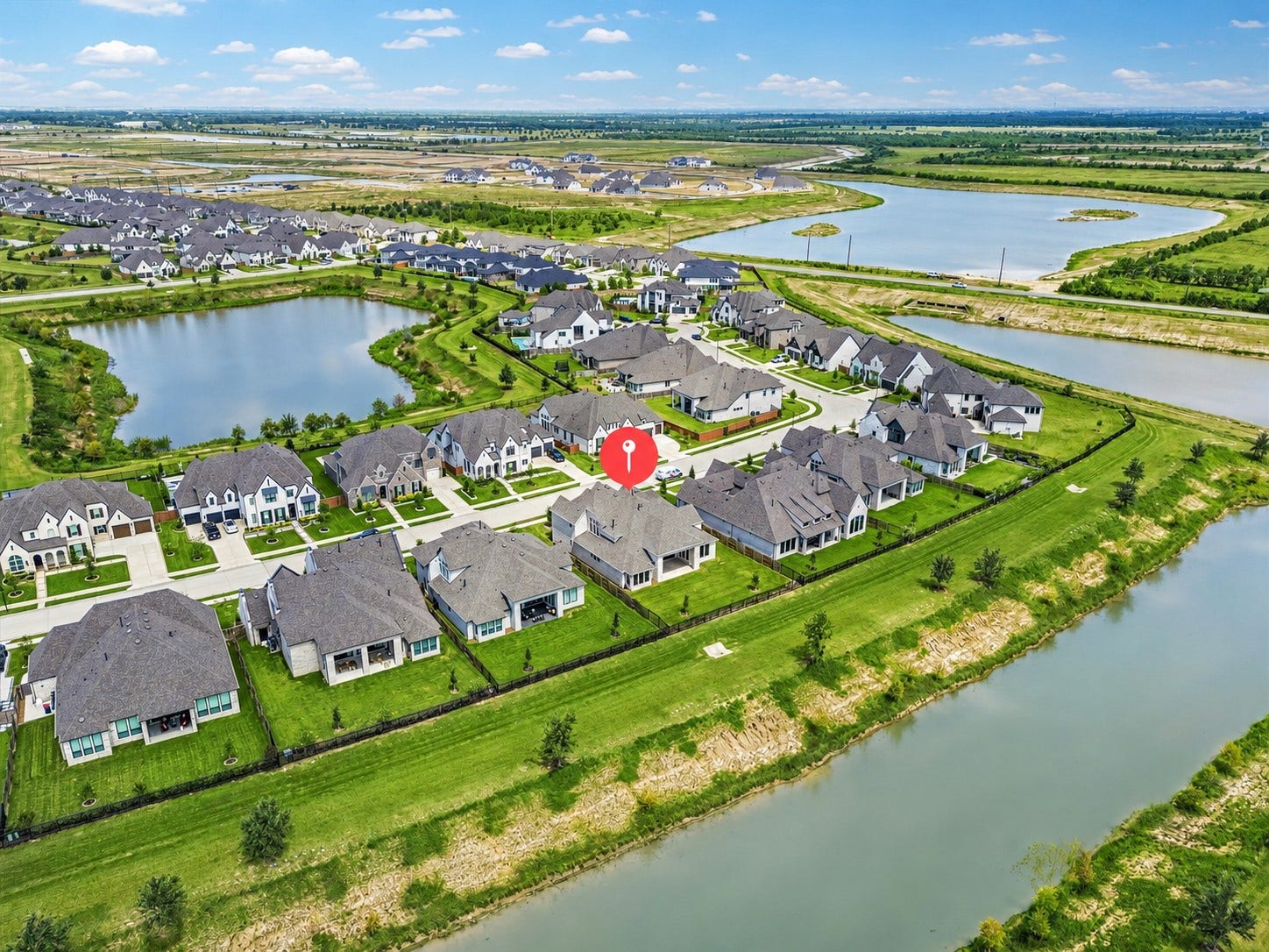 AERIAL VIEW OF 7802 ASHY SUNFLOWER LANE IN ELYSON, HIGHLIGHTING THE HOMES LOCATION NEAR NEIGHBORHOOD LAKES, GREEN SPACE, AND SURROUNDING RESIDENTIAL DEVELOPMENT.