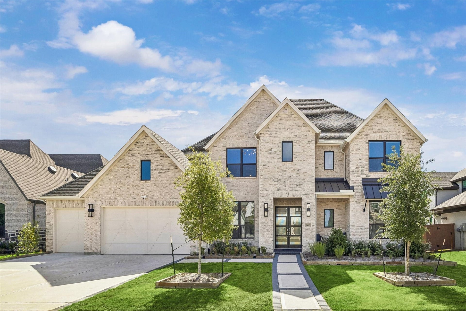 FRONT VIEW SHOWCASES THE LIGHT BRICK EXTERIOR, MODERN BLACK-FRAMED WINDOWS, LANDSCAPED YARD, AND CONTEMPORARY DOUBLE-DOOR ENTRY.