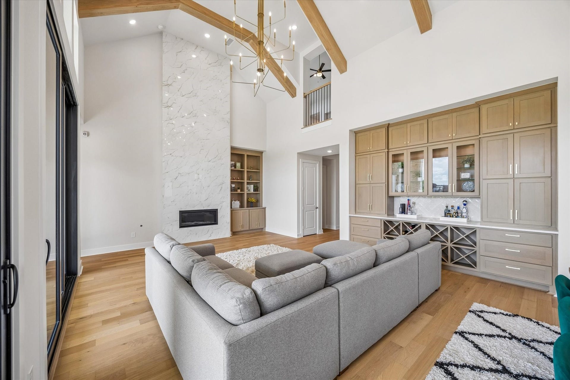 THIS SPACIOUS FAMILY ROOM FEATURES A DRAMATIC FIREPLACE SURROUND, CUSTOM BUILT-INS, AND DOUBLE-HEIGHT CEILINGS. UPPER-LEVEL OPENINGS AND CLEAN ARCHITECTURAL LINES ENHANCE THE ROOMS OPEN FEEL.