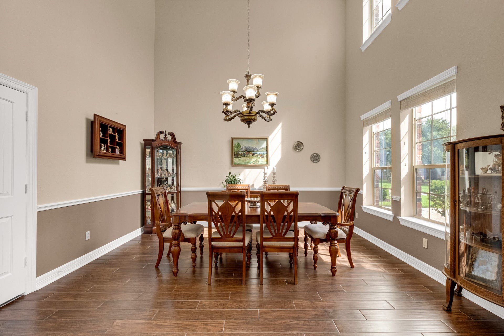 440 Old Orchard Court, Dickinson, TX 77539 The formal dining room rises a full two stories, crowned by an ornate chandelier, with a chair-rail wainscot and a tall window bank that keeps the space bright without losing its formality.