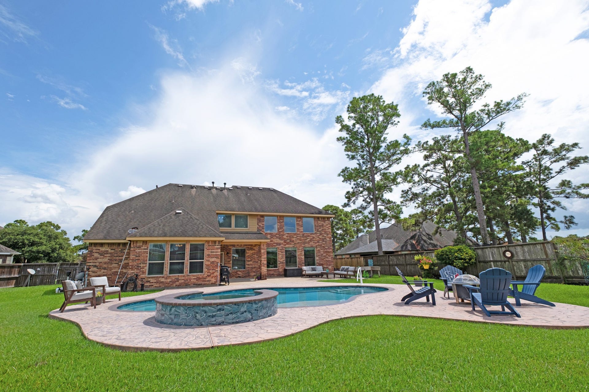 440 Old Orchard Court, Dickinson, TX 77539 From the grass you see the whole rear composition: covered patio, pool, spa, and a fenced yard that keeps its distance from the neighbors.