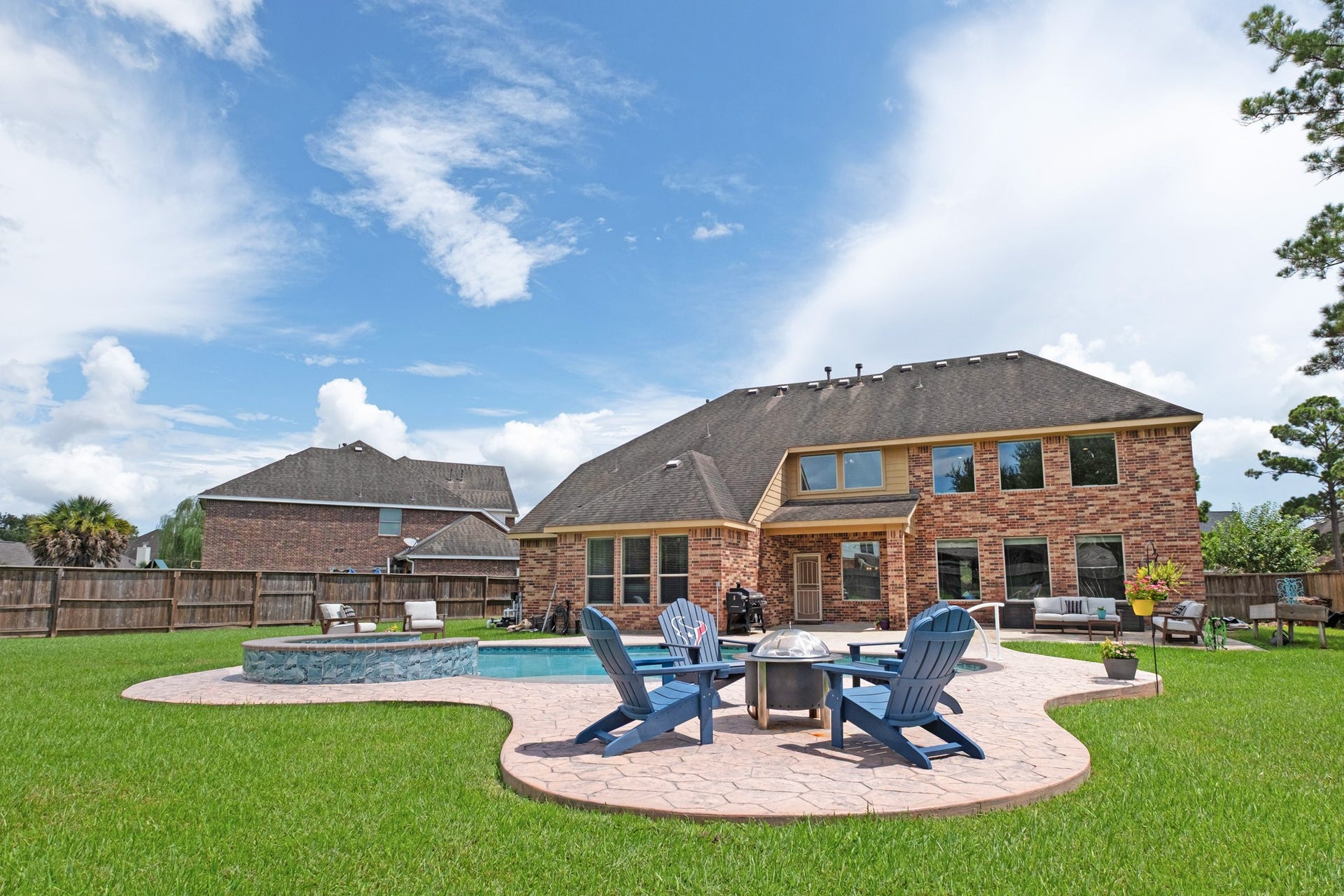 440 Old Orchard Court, Dickinson, TX 77539 Out back, the story shifts to resort living - a freeform saltwater pool with a raised stone-faced spa, a sweeping stamped concrete deck, a fire pit gathering circle, and still a generous run of turf beyond the coping.