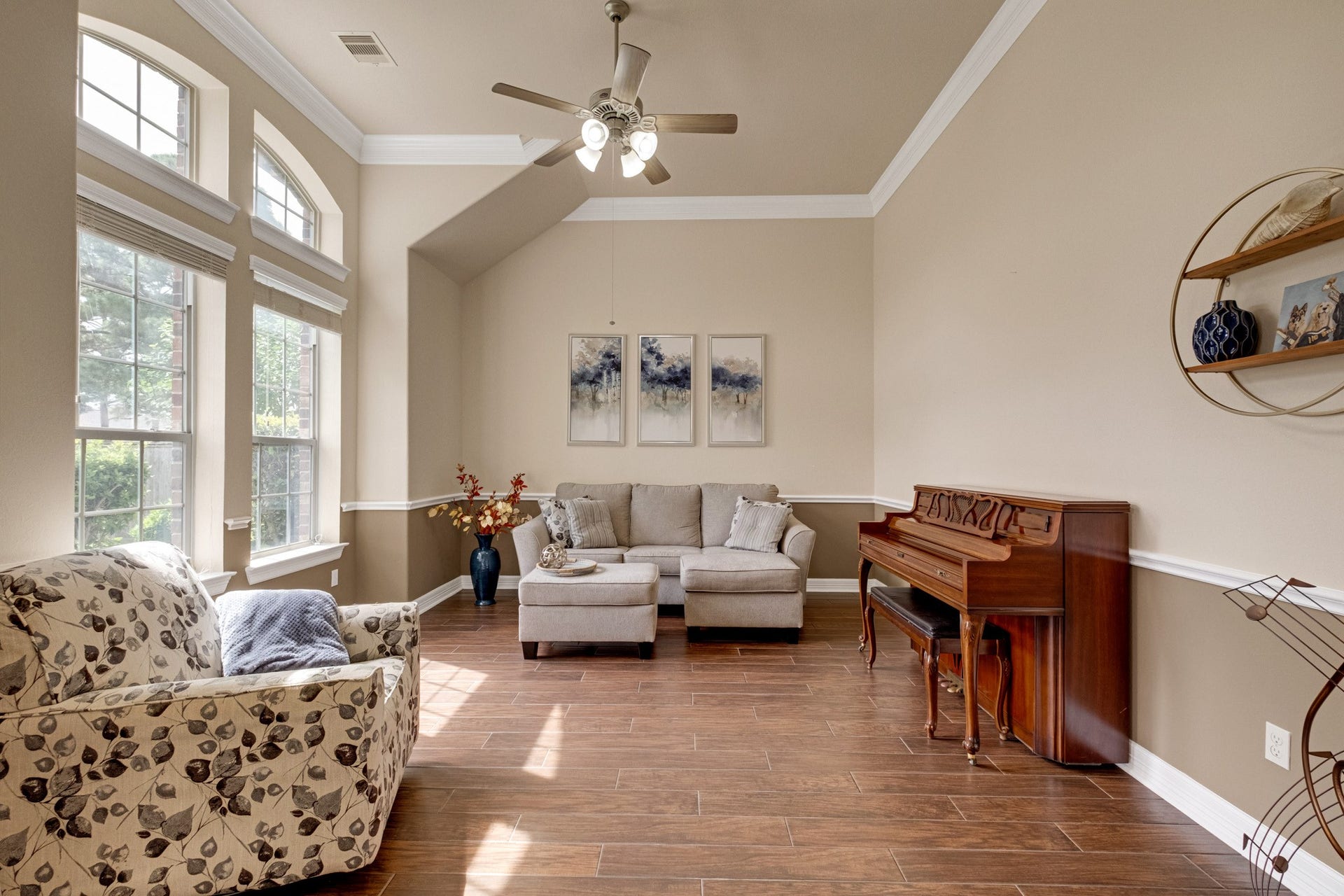 440 Old Orchard Court, Dickinson, TX 77539 The formal living room lifts into a vaulted ceiling with crown molding, lit by tall arched windows and grounded by a two-tone wall treatment with chair rail.