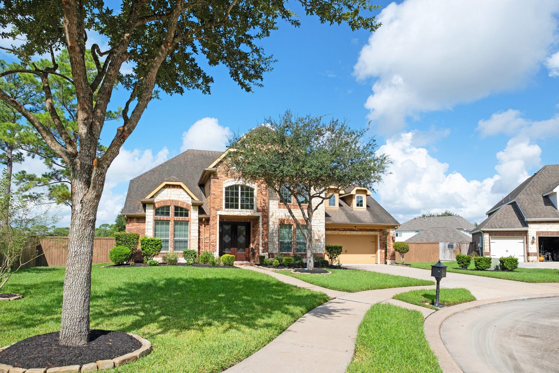440 Old Orchard Court, Dickinson, TX 77539 Set on the bulb of the cul-de-sac, the lot stretches wide across a deep front lawn with a mature live oak and dual walkways feeding the entry and the drive.