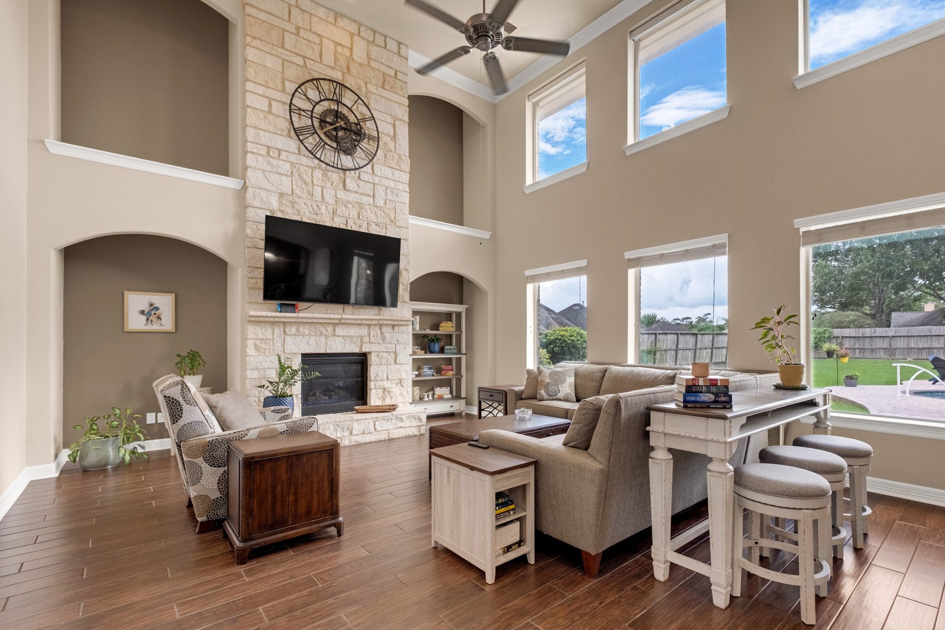 440 Old Orchard Court, Dickinson, TX 77539 The family room reads best from the kitchen side: the stone chimney breast climbing to the ceiling, arched niches stacked on both walls, and clerestory windows above the main bank for a second layer of light.