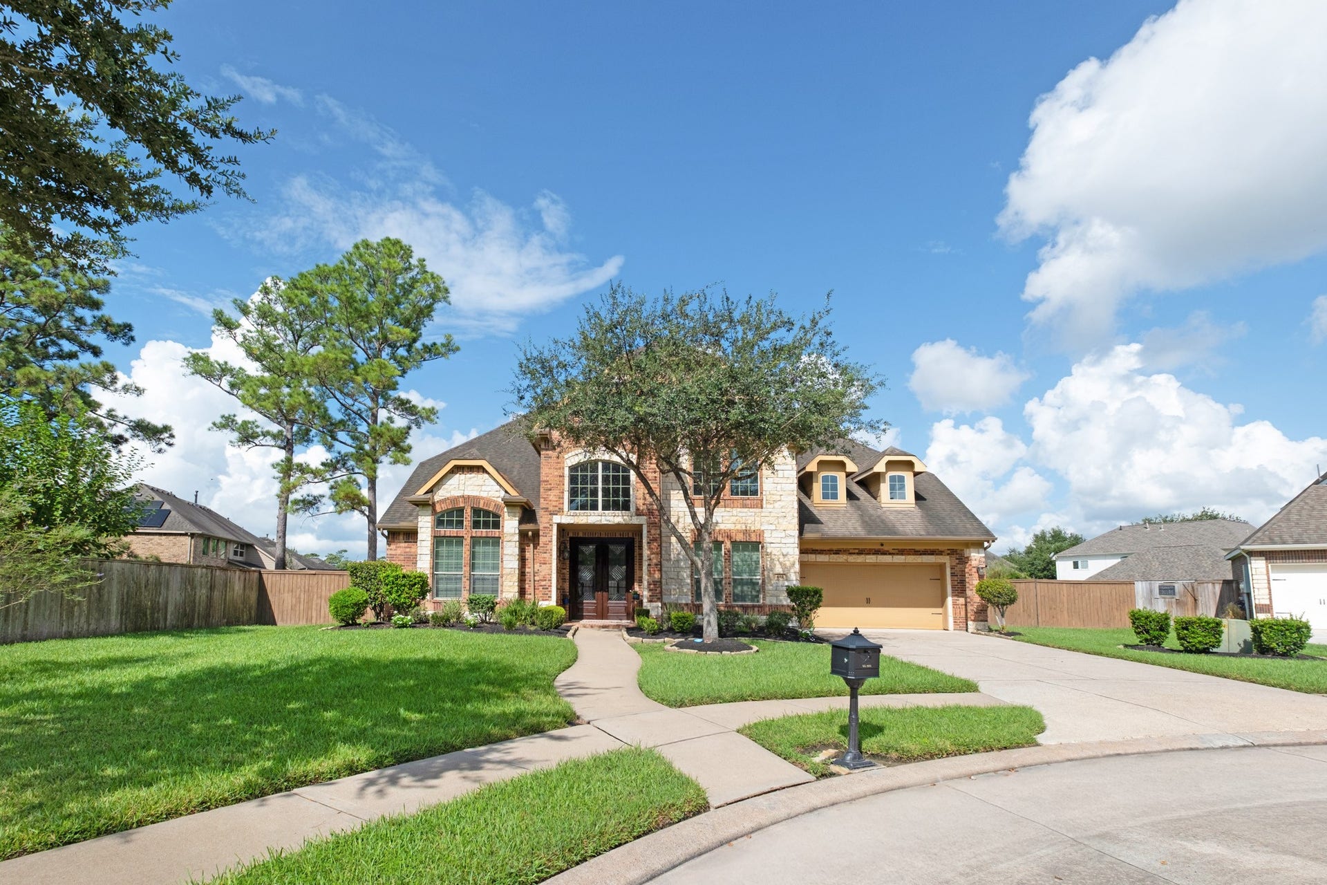 440 Old Orchard Court, Dickinson, TX 77539 Head-on, the symmetry comes together - steep gables over the stone-faced entry, twin dormers stepping down toward the garage, and an oversized drive with room to turn.