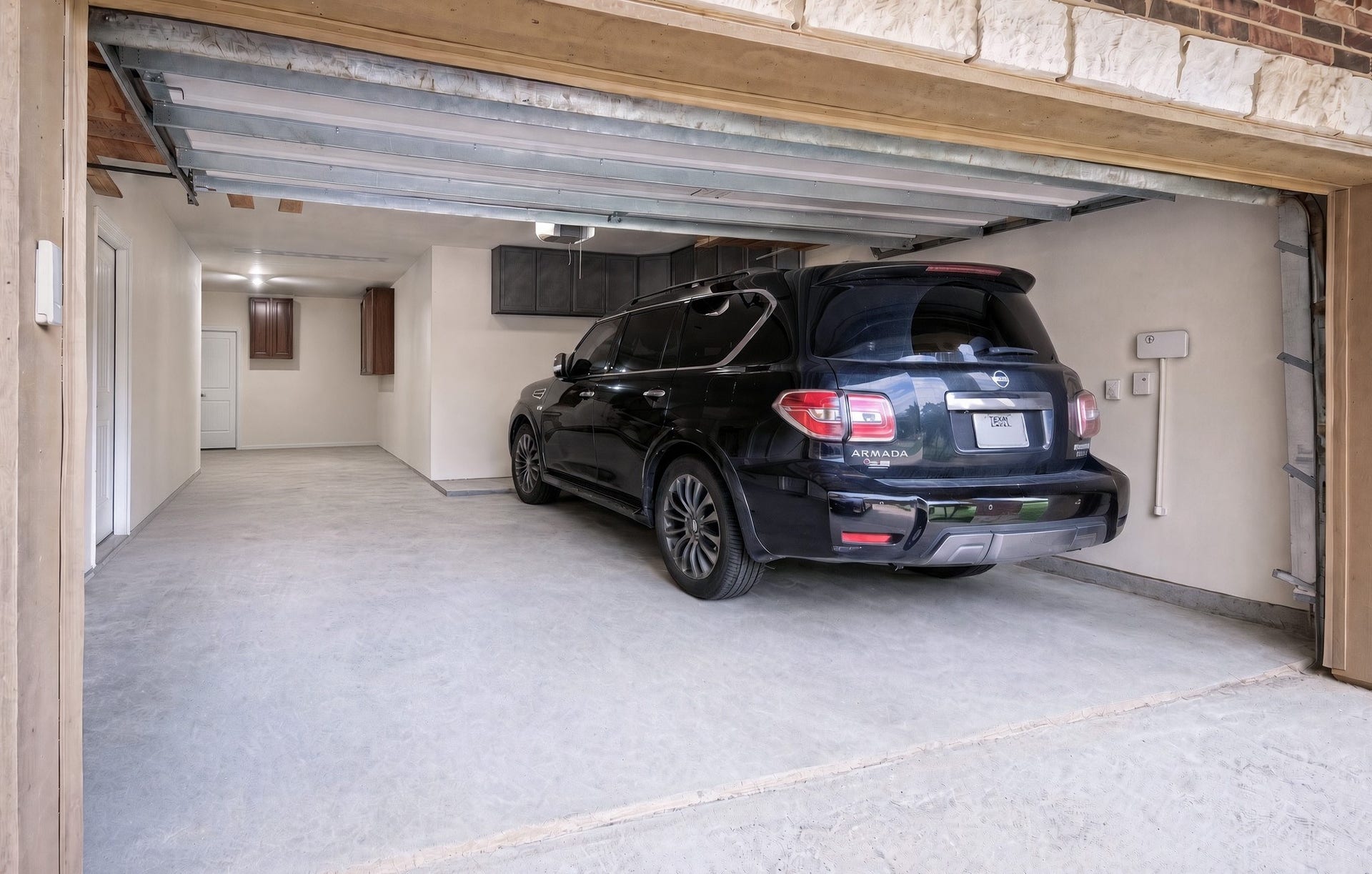 440 Old Orchard Court, Dickinson, TX 77539 That is a full-size SUV in the right-hand bay, and it fits with room to spare - the clearest measure of how deep and wide this attached three-car tandem garage runs. The tandem bay beside it still takes a third vehicle, a workshop bench, or the lawn equipment, with overhead cabinet storage and direct interior access.