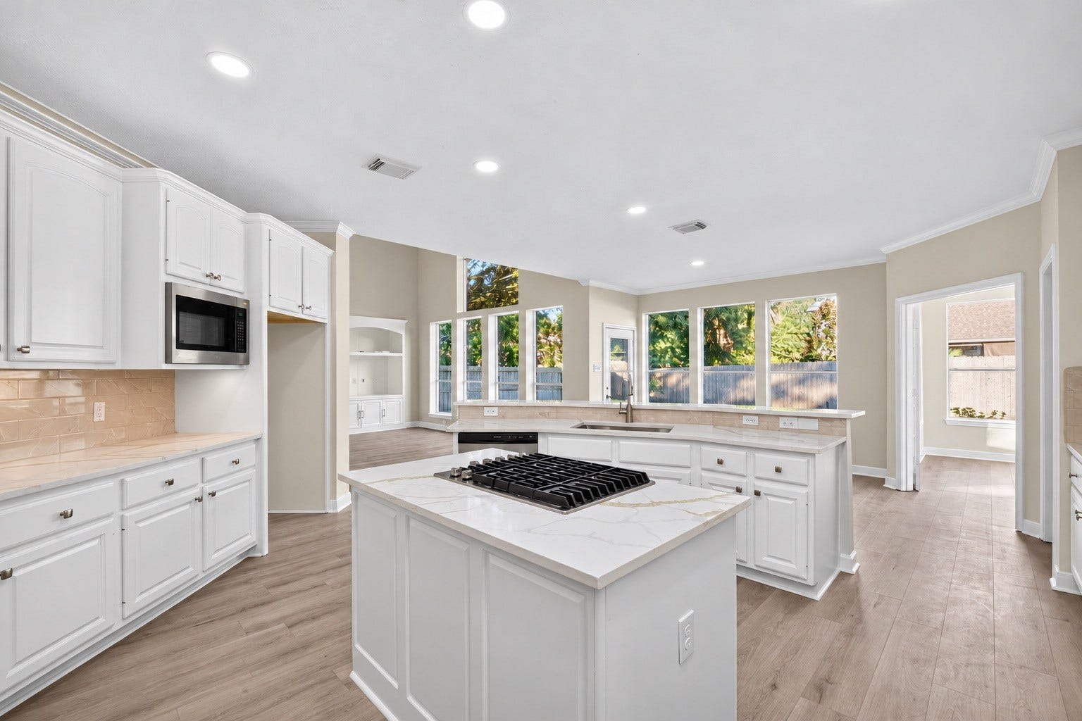 3610 Forest Row Drive, Houston, TX 77345 Natural light fills this open kitchen with an island cooktop, generous counter space, and abundant cabinet storage. The sink overlooks the adjoining living and breakfast areas. Appliance finishes digitally enhanced.