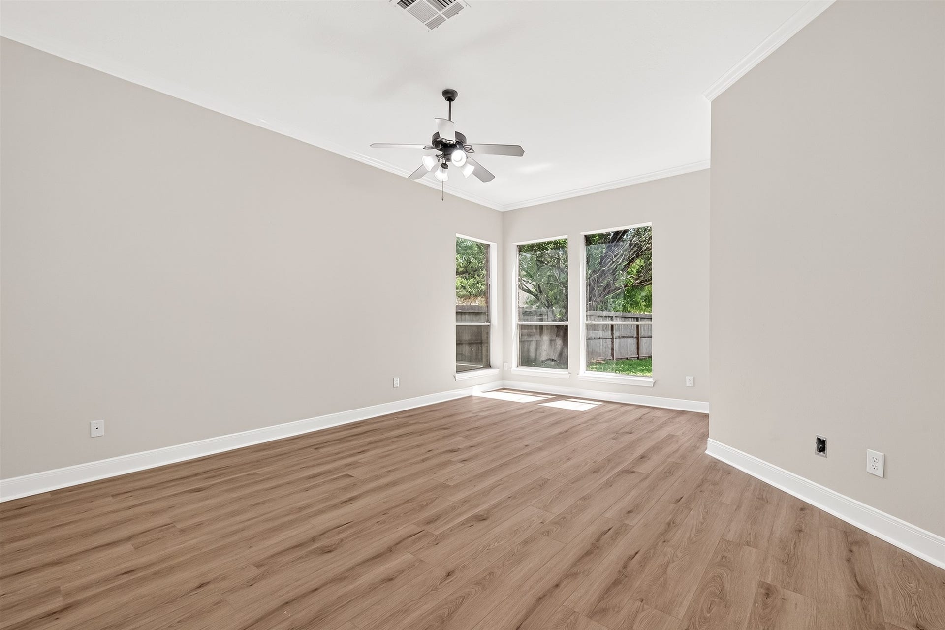 3610 Forest Row Drive, Houston, TX 77345 Spacious room with elegant wood flooring, abundant natural light from large windows, and a stylish ceiling fan.