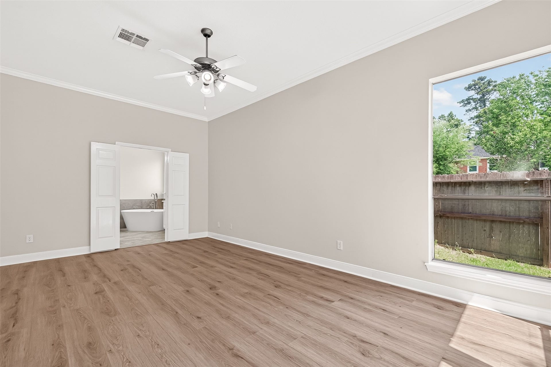 3610 Forest Row Drive, Houston, TX 77345 Spacious room with elegant wood flooring, abundant natural light, and direct access to a luxurious bathroom featuring a modern freestanding tub.